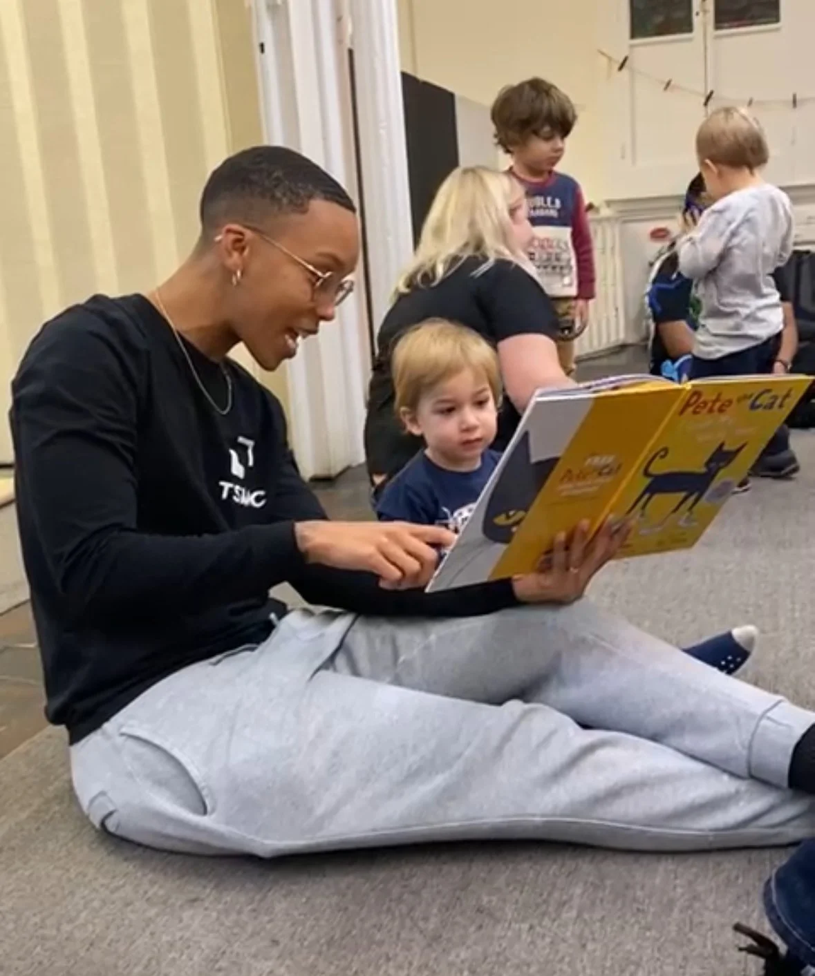 Teacher sitting with a student reading a book.