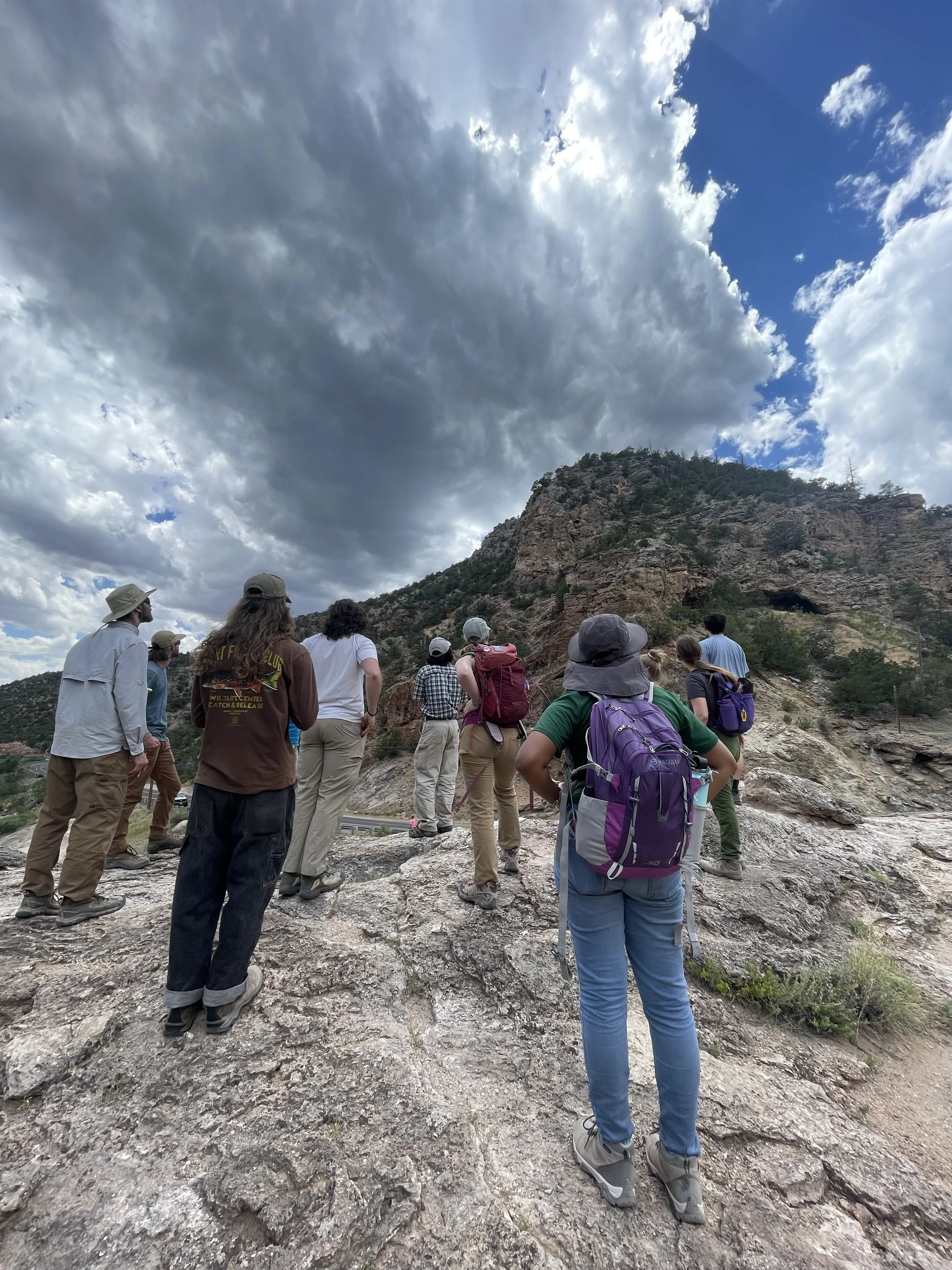 SAGE, Summer of Applied Geophysical Experience. Group of people on a hike in mountainous terrain with cloudy sky.