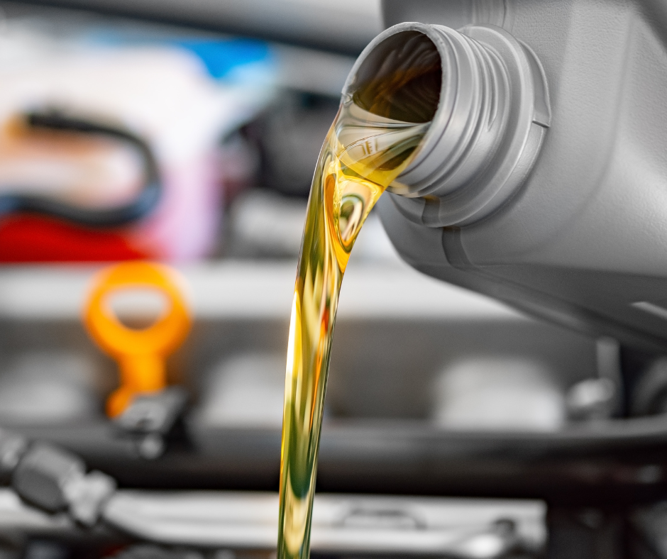 Motor oil pouring from a container into a car engine.