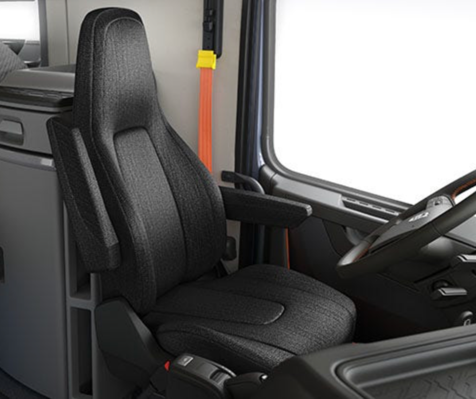 Interior of a truck cab featuring a black driver’s seat, steering wheel, and a large window.