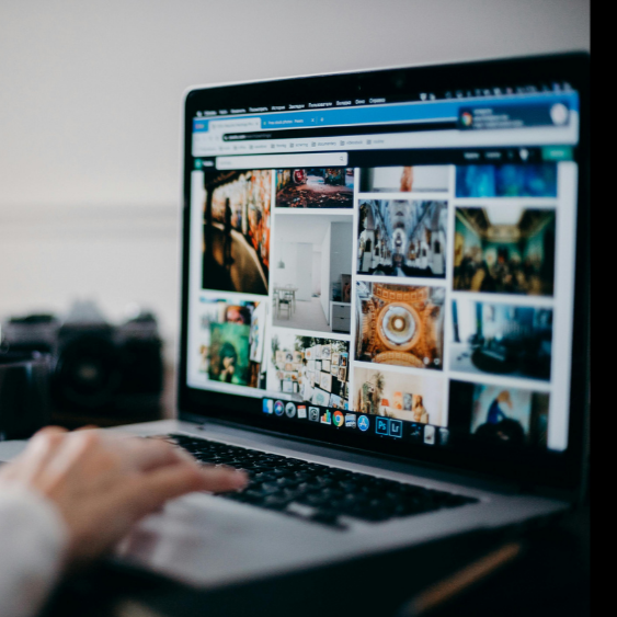 Laptop screen displaying a gallery of various images including interiors and landscapes, with a person's hand on the keyboard.