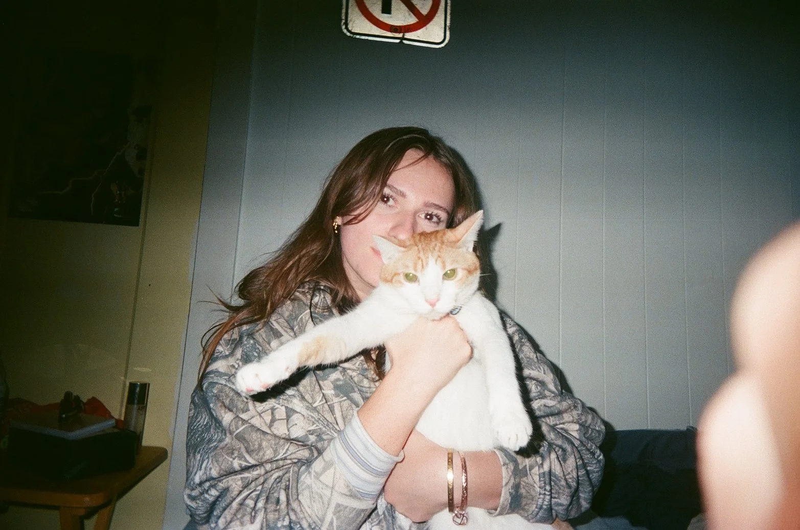 A young woman holding a large orange and white cat in an indoor setting.