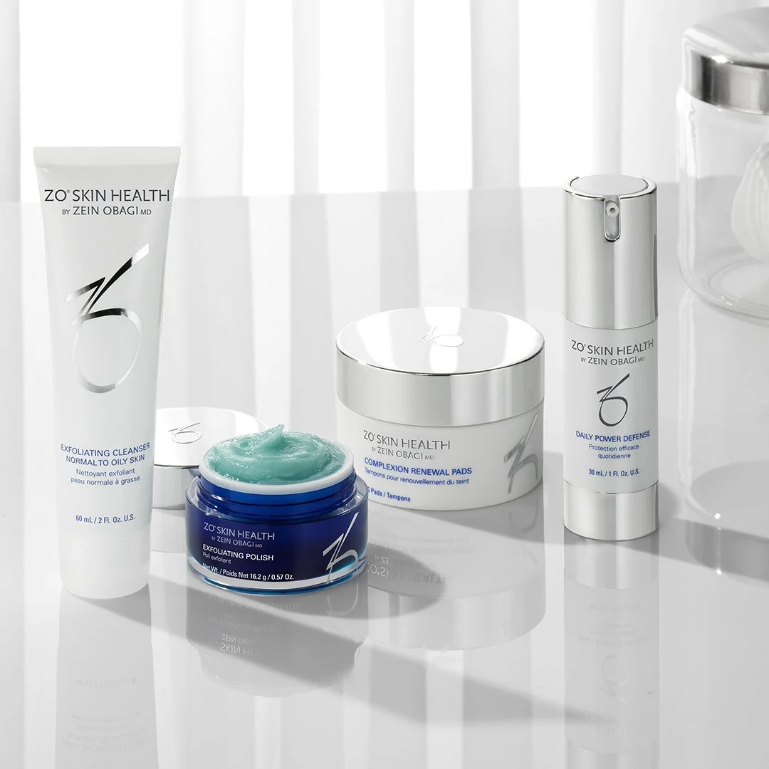 Collection of skincare products from ZO Skin Health by Zein Obagi, including exfoliating cleanser, renewal pads, exfoliating polish, daily power defense, and a jar of cream on a white surface with a white background.