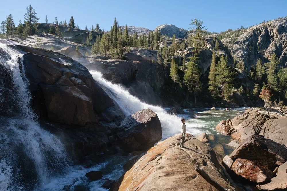 person standing at the edge of a waterfall
