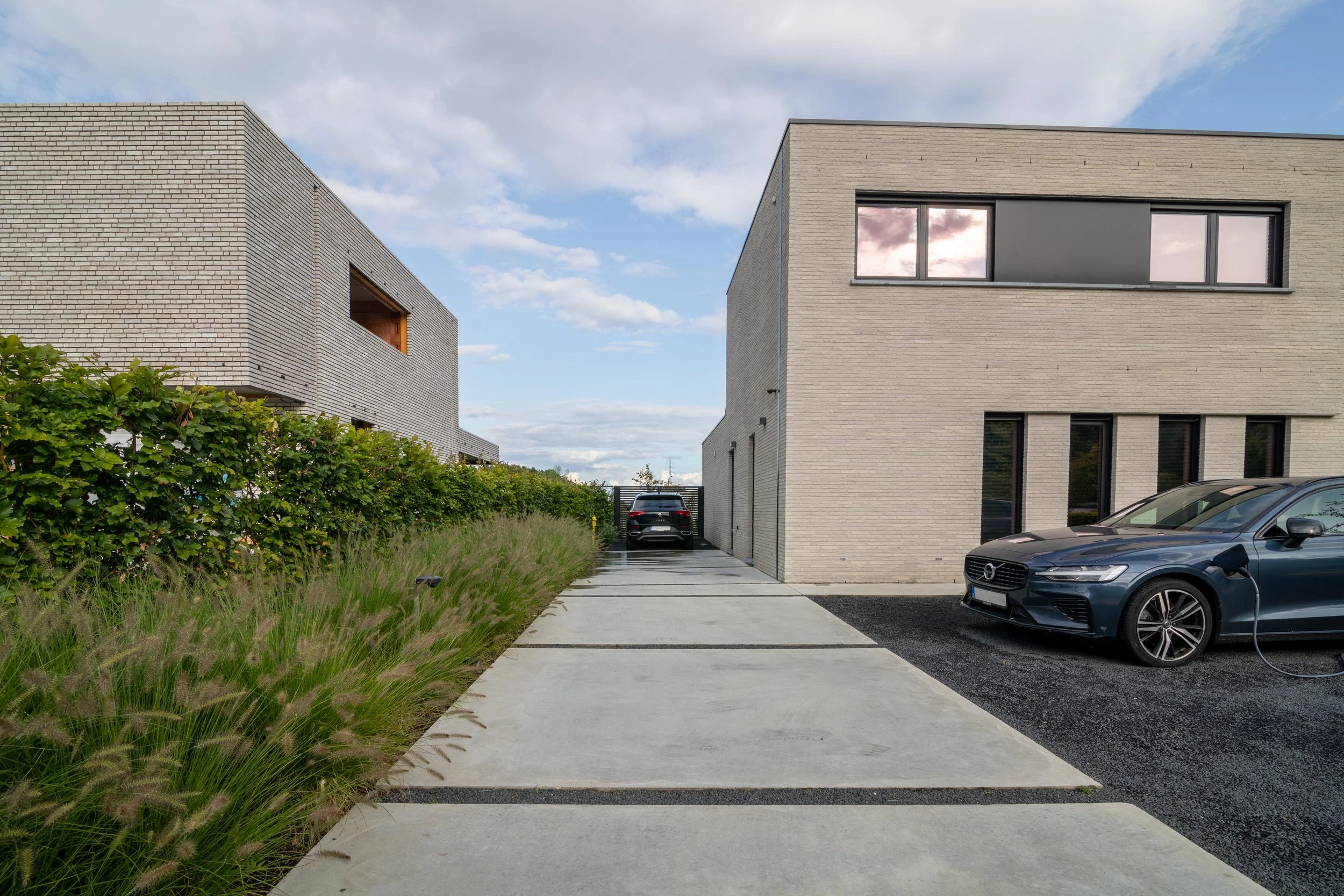 Moderne oprit met betonplaten, strakke beplanting en architecturale woning ontworpen door Tuinarchitect Florian