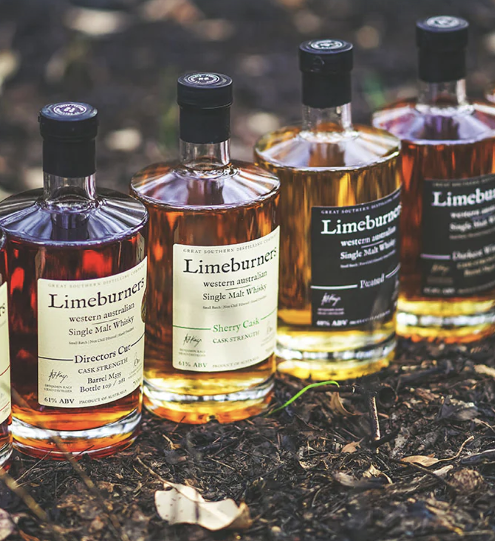 Four bottles of Limeburners single malt whiskey arranged on dirt outdoors, featuring labels for Directors Cut and Sherry Cask flavors.