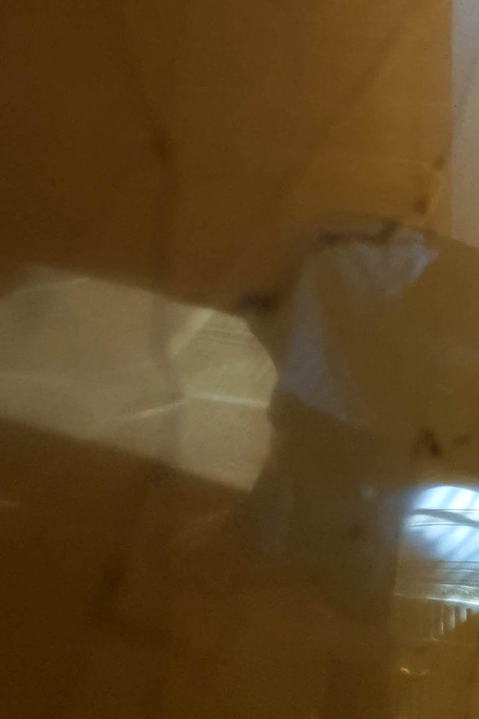 A close-up, blurry image of a reflective, shiny gold surface with light reflections.