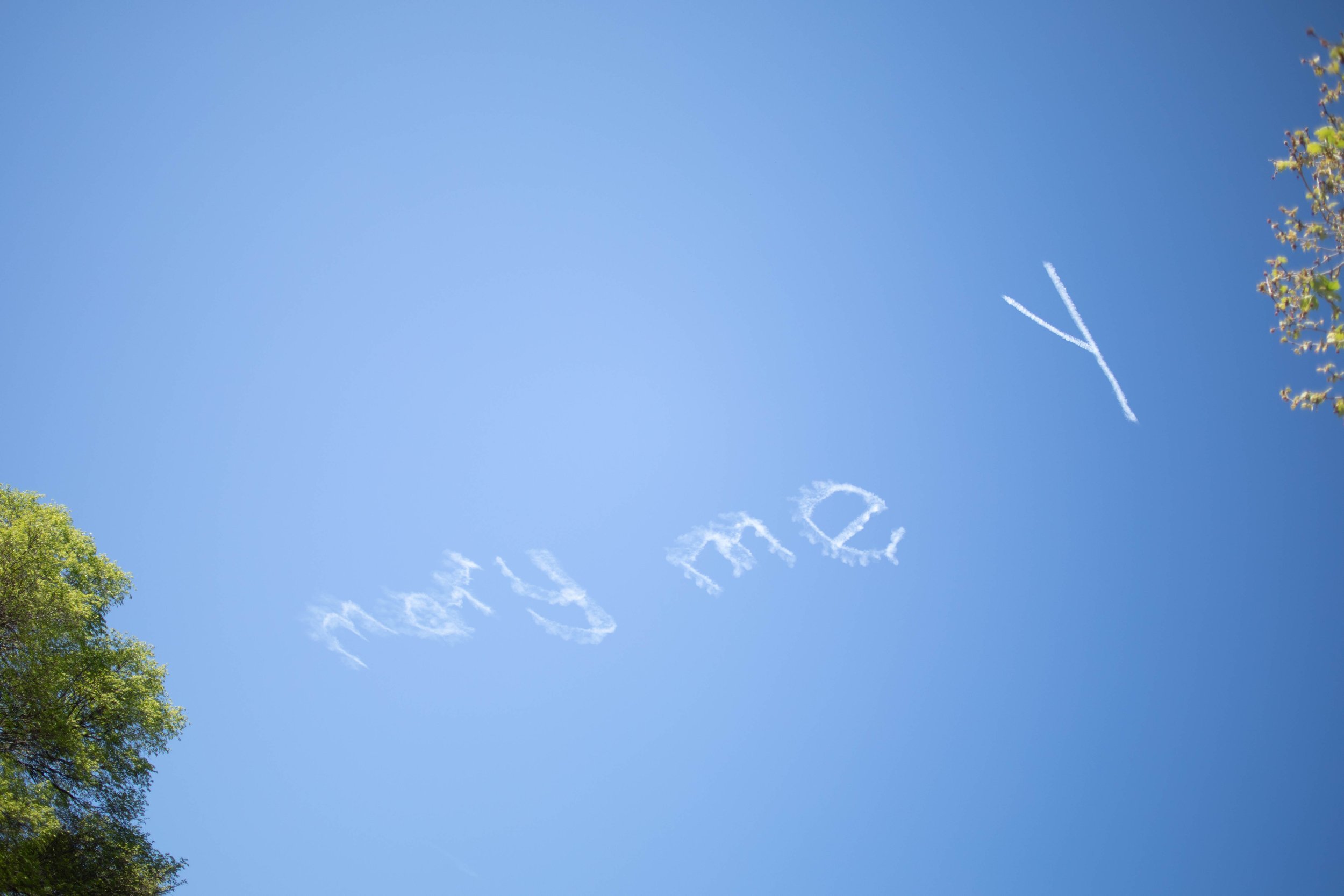 Clouds in the sky spelling out the word 'marry me' with a small airplane flying nearby.