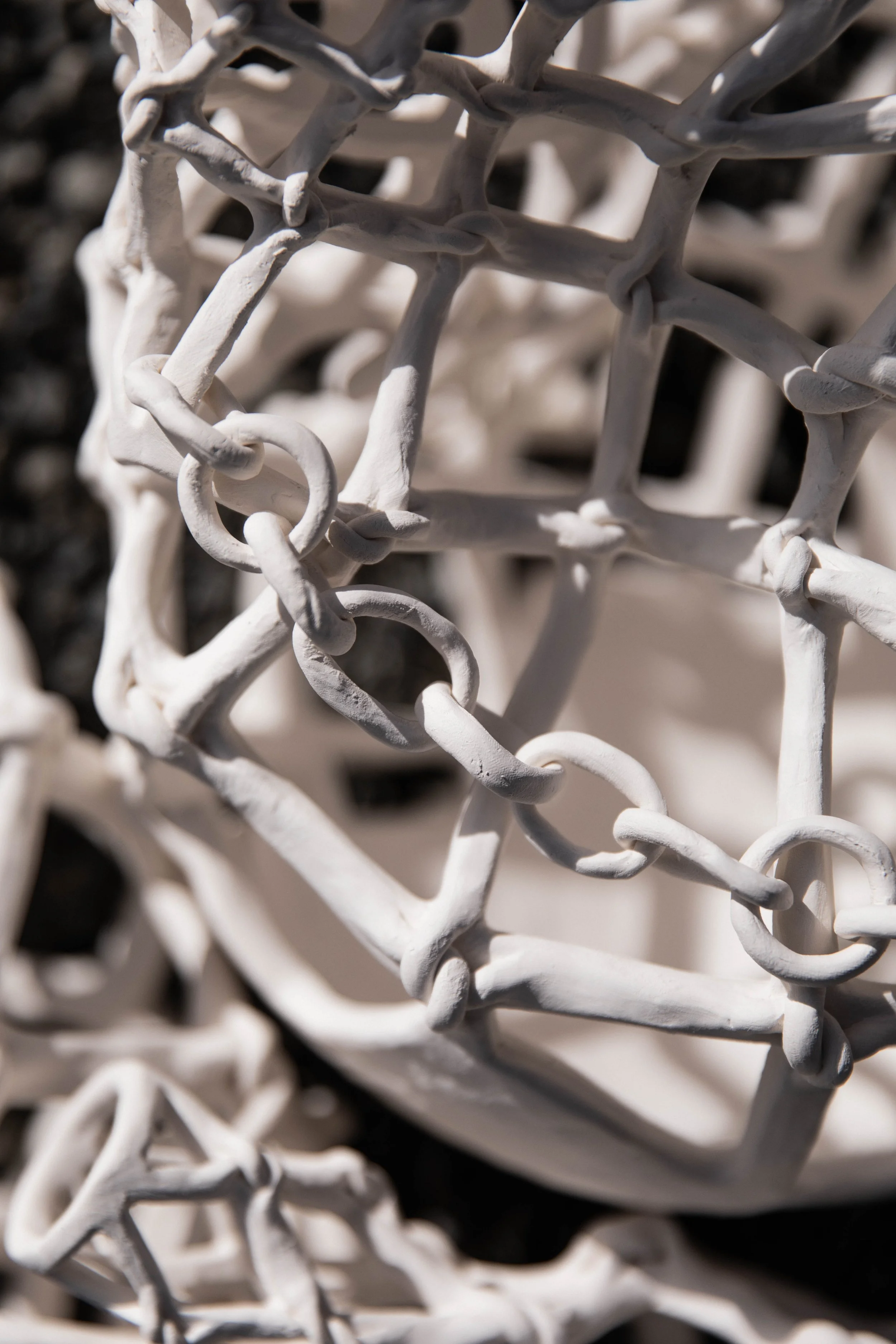 Close-up of a tangled white ceramic artwork resembling a metal chain link fence.