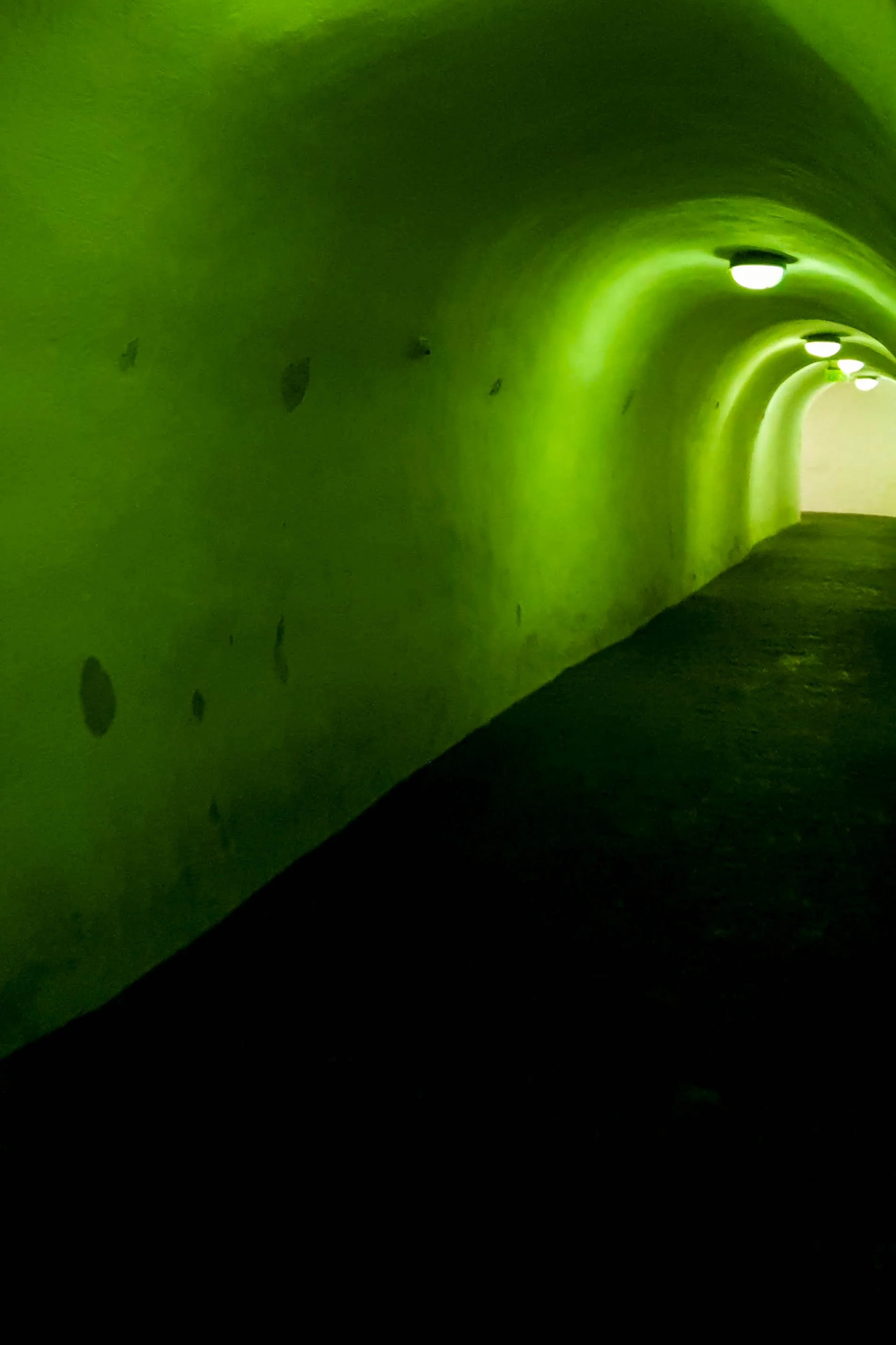 Underground tunnel with green walls and lit ceiling