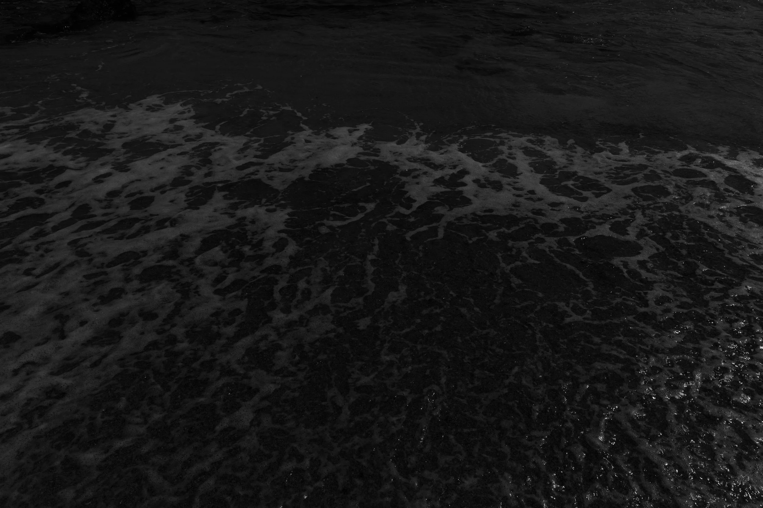 Dark ocean water with foamy waves near the shore.