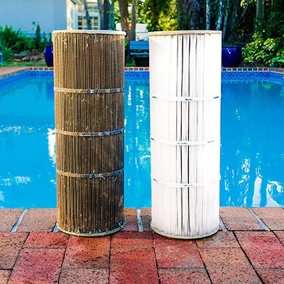 Two pool filters, one dirty and one clean, next to a swimming pool.