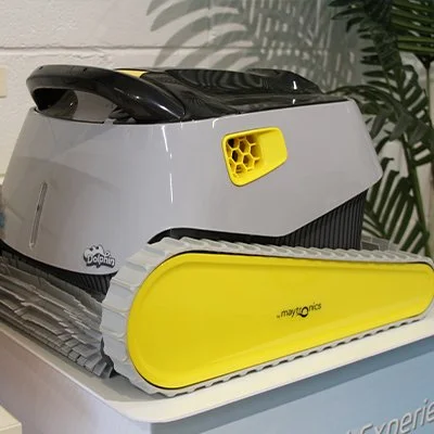 Robotic pool cleaner on display with yellow tracks and a sleek design, branded "Dolphin" by Maytronics.
