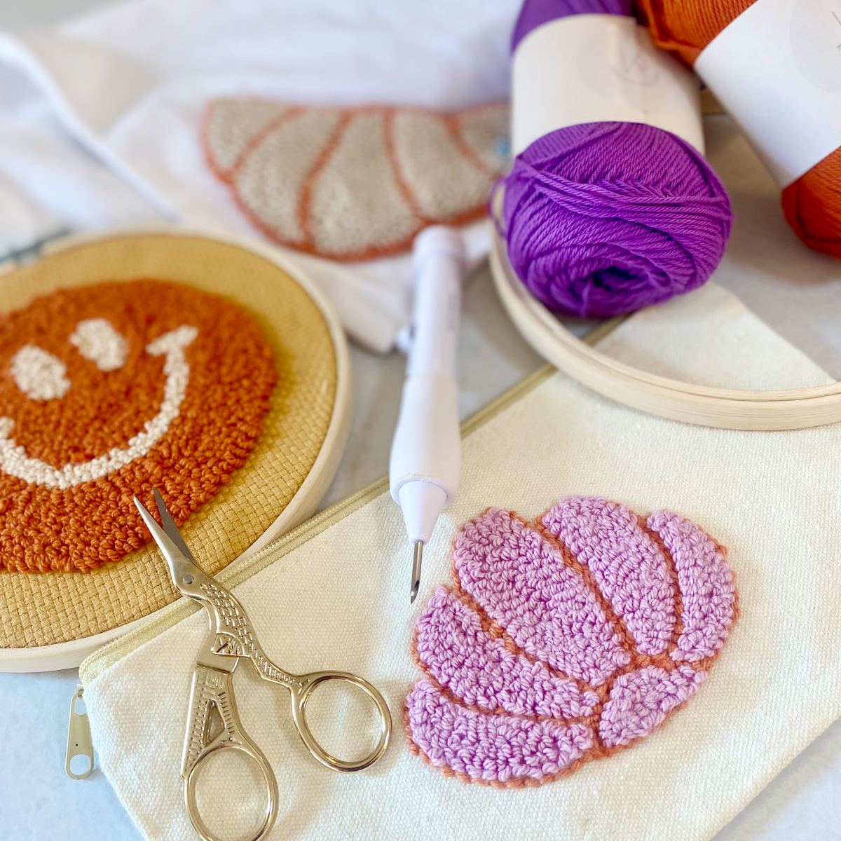 Strickzubehör mit pinkem und orangefarbenem Garn, Nähte und Strickmaschinen. Ein Ausdruck einer lächelnden Gesichts-Zeichnung auf einer gestrickten Fläche.