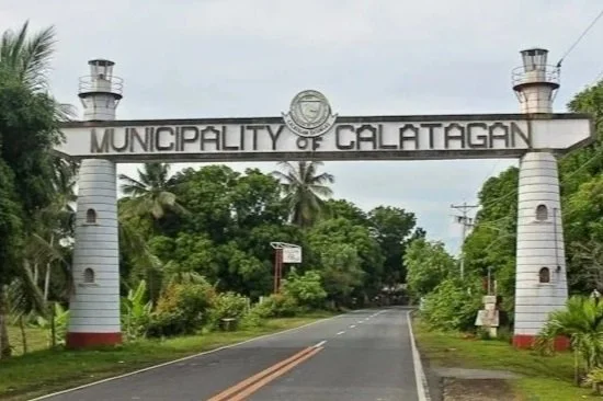 Entrance archway of the Municipality of Calatagan with two lighthouse-shaped pillars and lush greenery in the background.