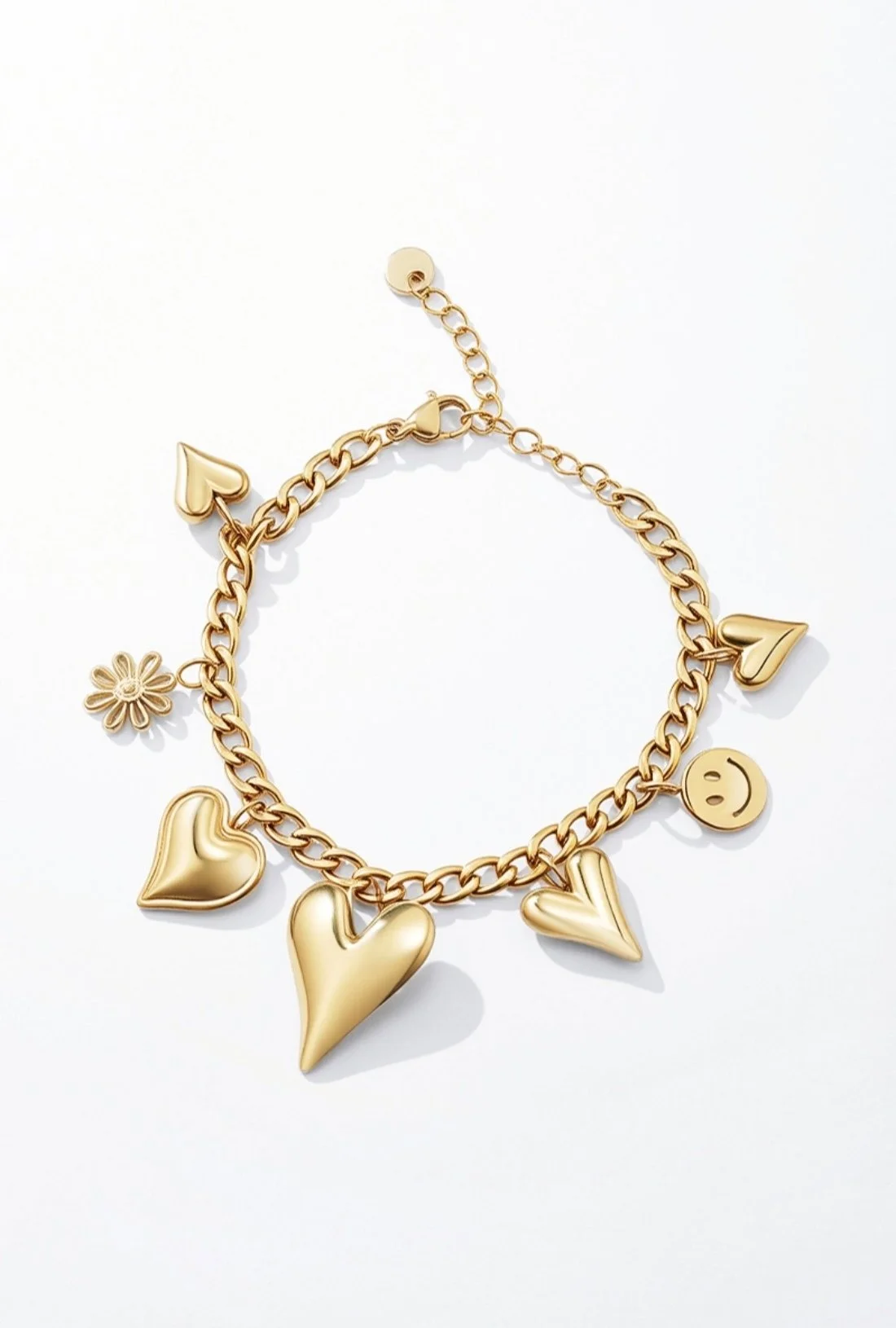 Bracelet en or avec pendentifs en forme de cœur, d'étoile, de sourire, de fleur, et d'un triangle, posé sur un fond blanc