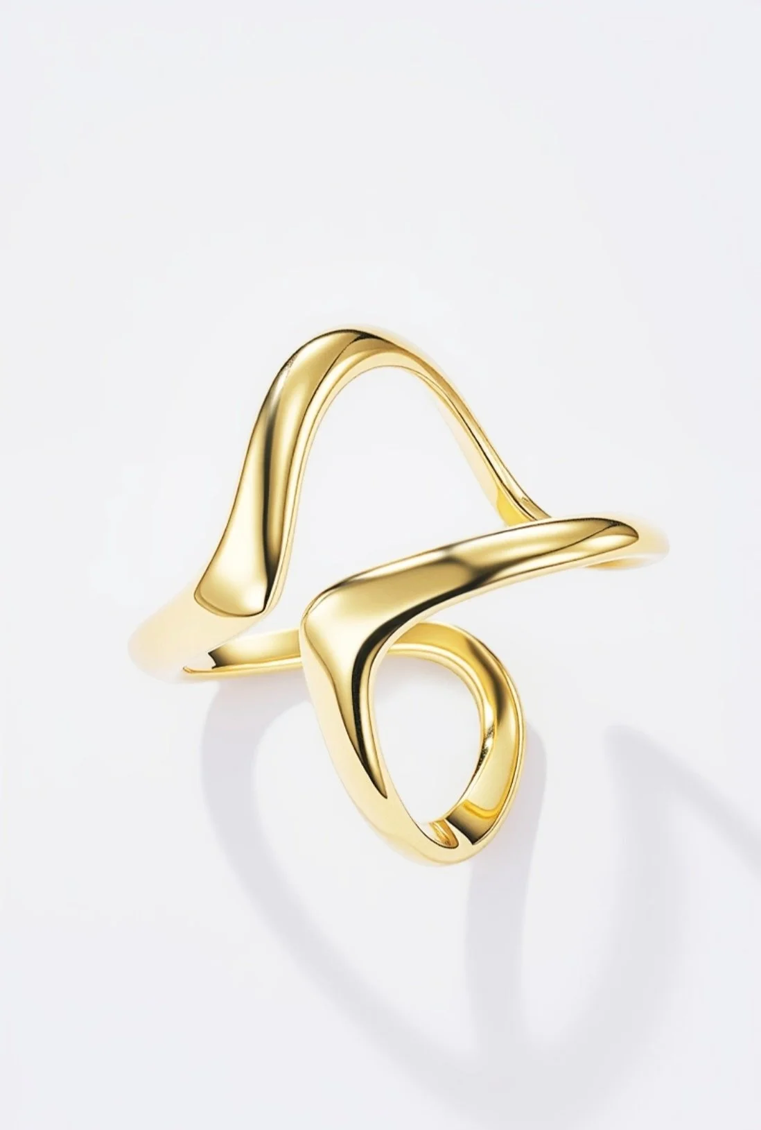 Bague en or avec un design fluide et moderne sur fond blanc.