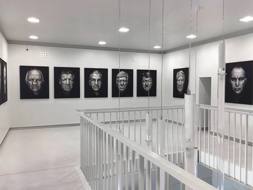 Galerie d'art avec portraits en noir et blanc de visages humains sur le mur.