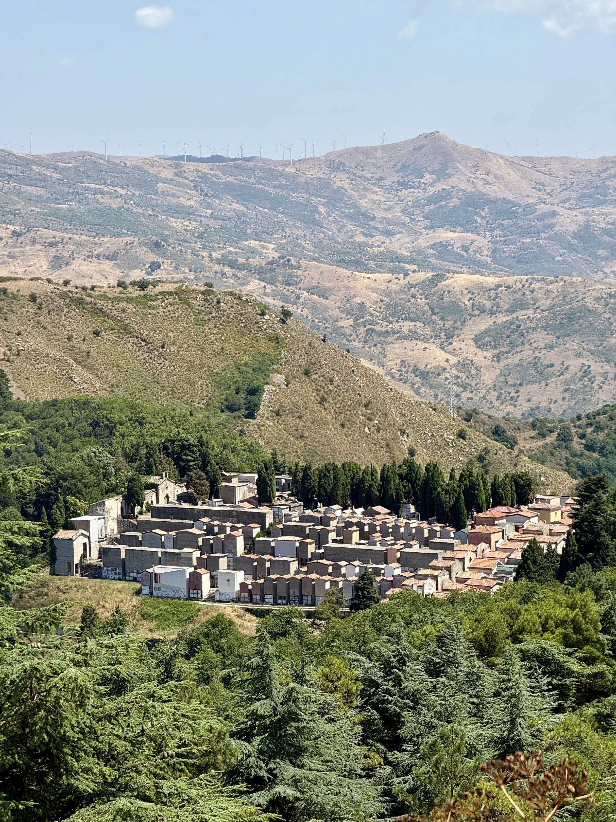 An aerial view of the cemetery in San Mauro Castelverde, Sicily surrounded by green, wooden mountains