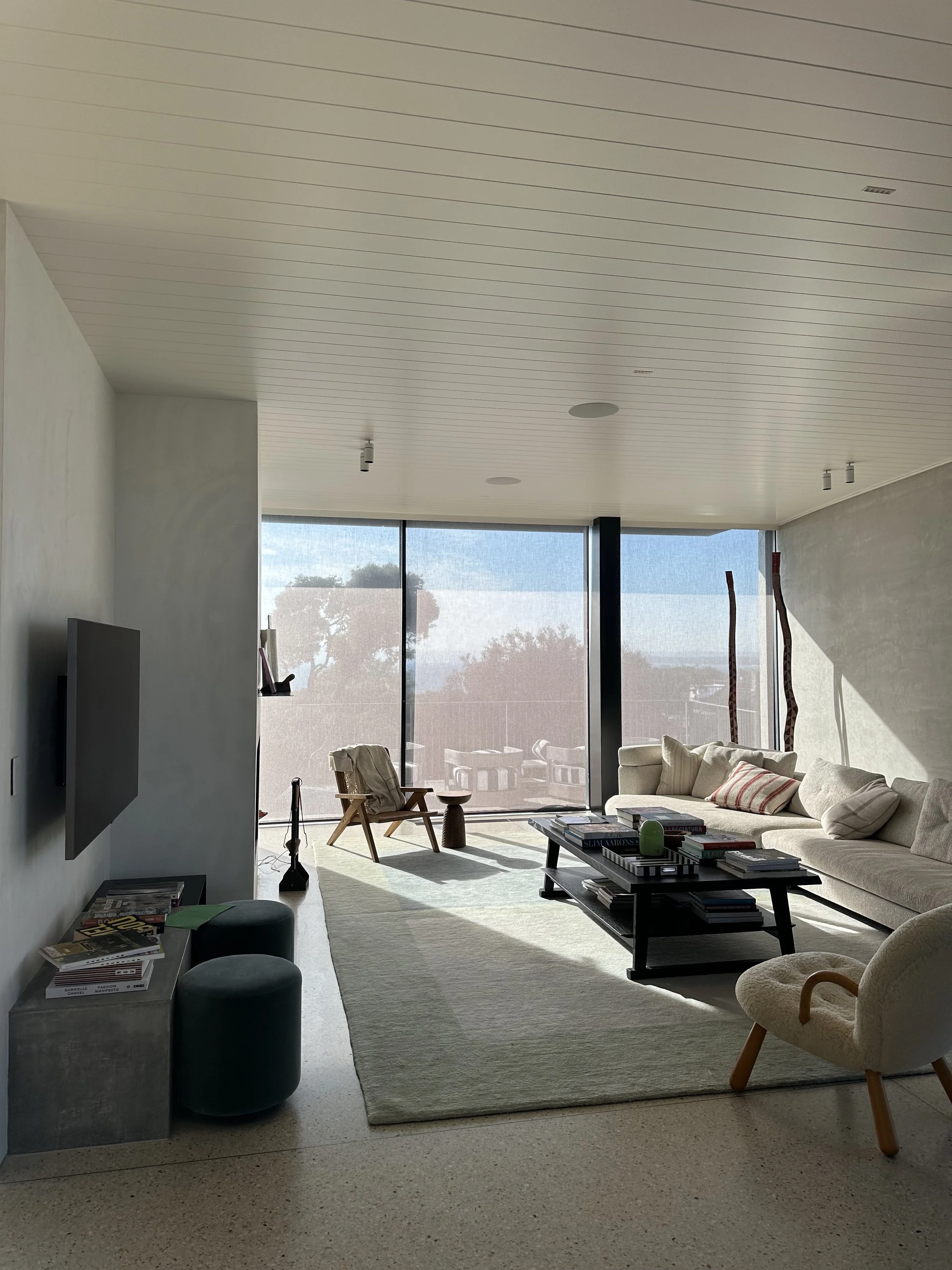 Modern living room with a large window, white sofa, armchair, coffee table, and minimal decor.