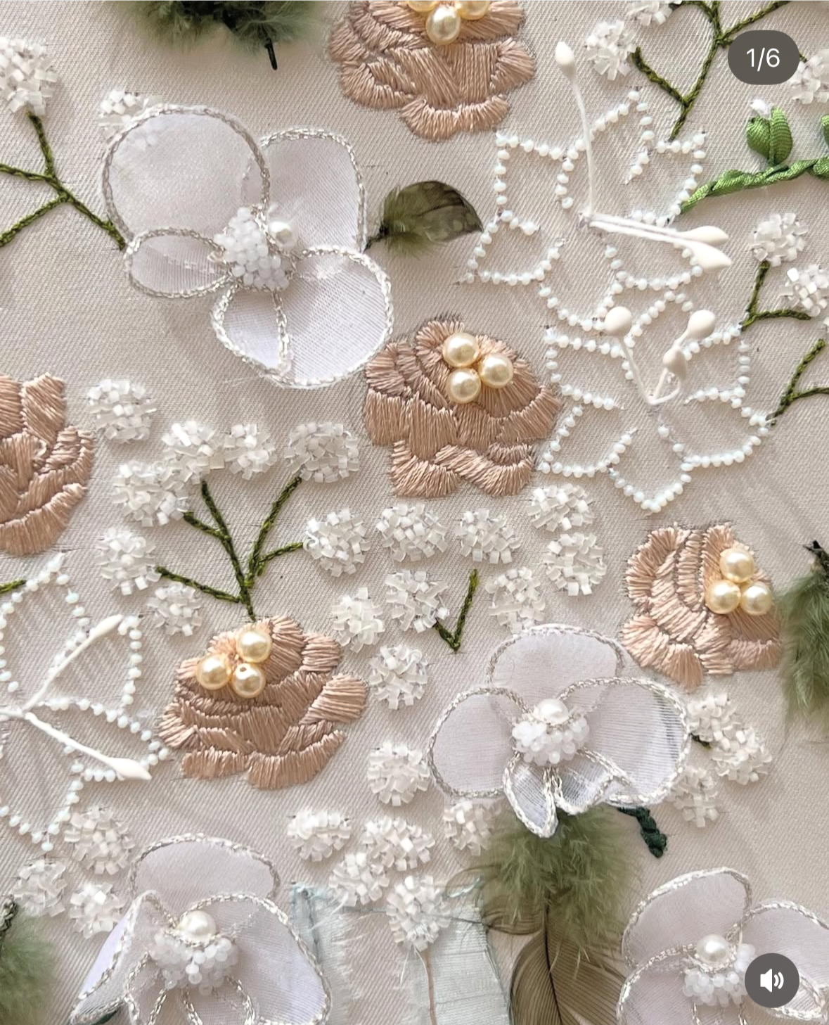 Broderie florale avec des fleurs en satin beige, des pétales en perles, des fleurs en tulle blanc, et des broderies en fil blanc avec des détails en perles.