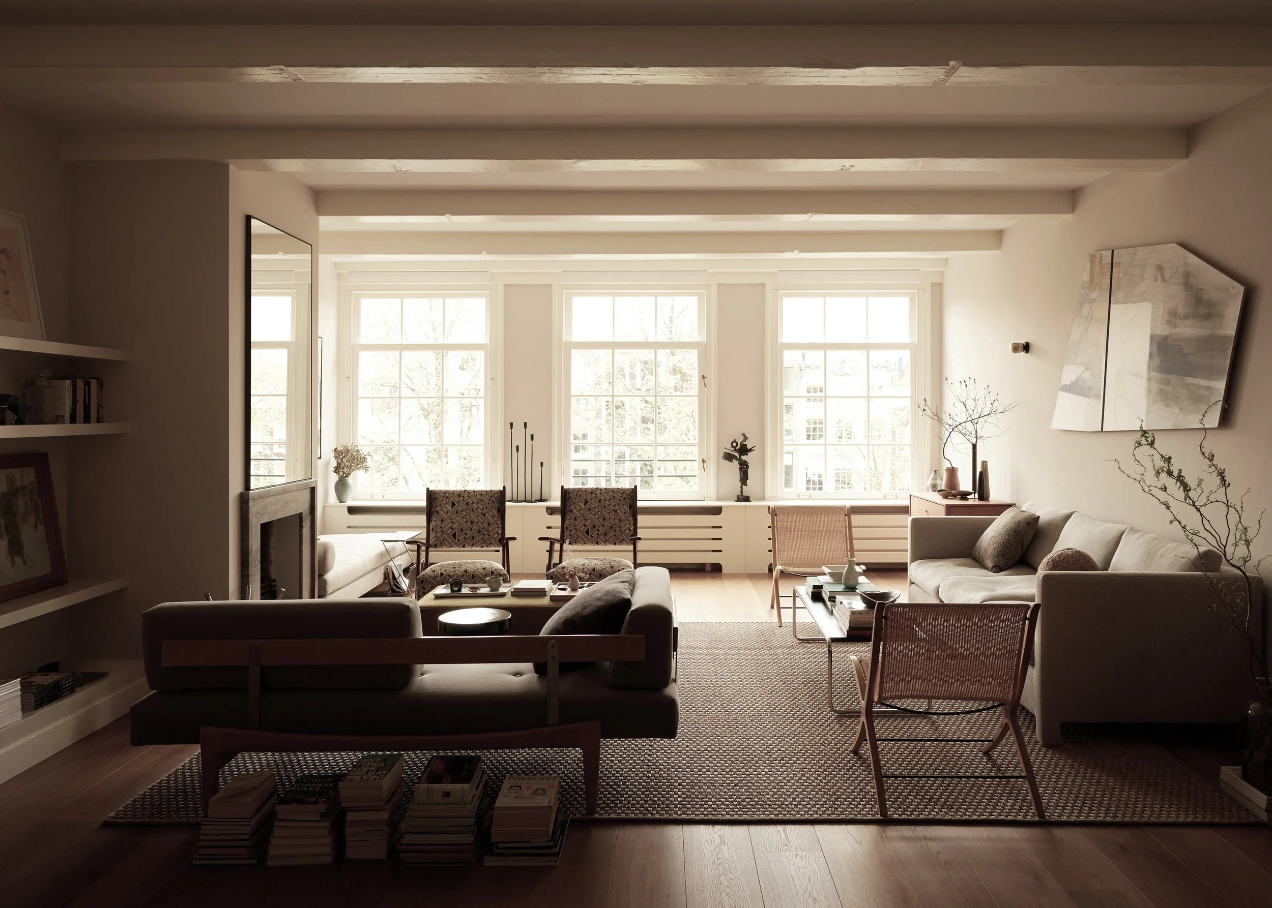Modern living room with natural light, beige walls, sofa, armchairs, and large windows. Minimalist decor with bookshelf and plants.
