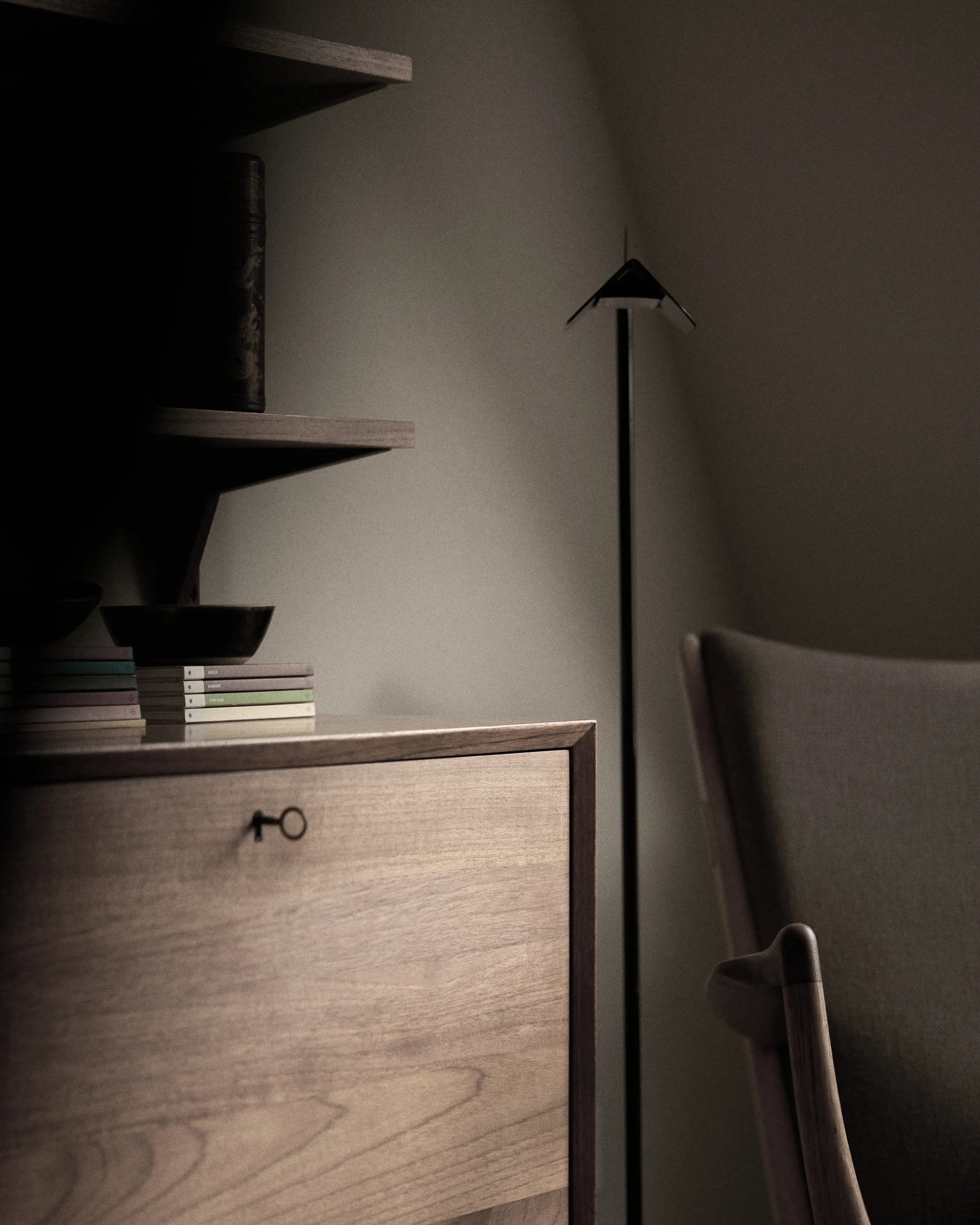 Minimalist interior with a wooden cabinet, a stack of books, and a modern chair.