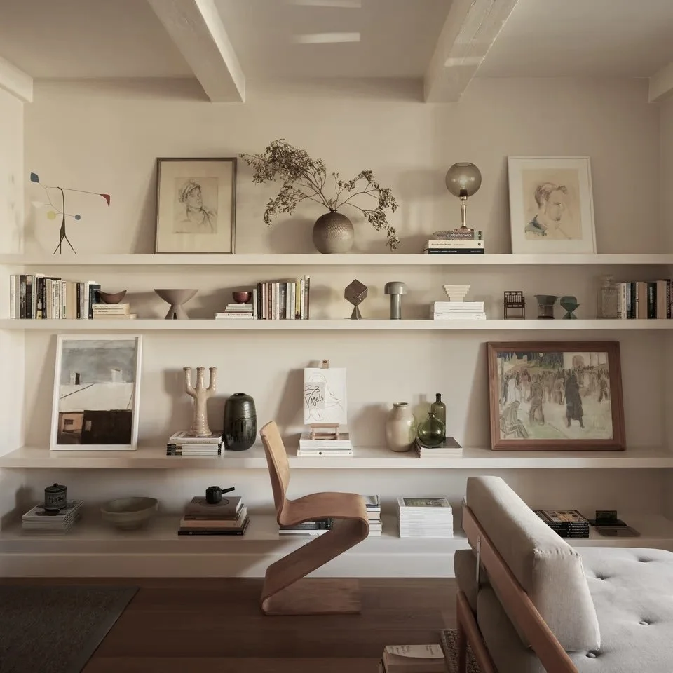 Interior room with shelves, books, artwork, vases, and a wooden chair