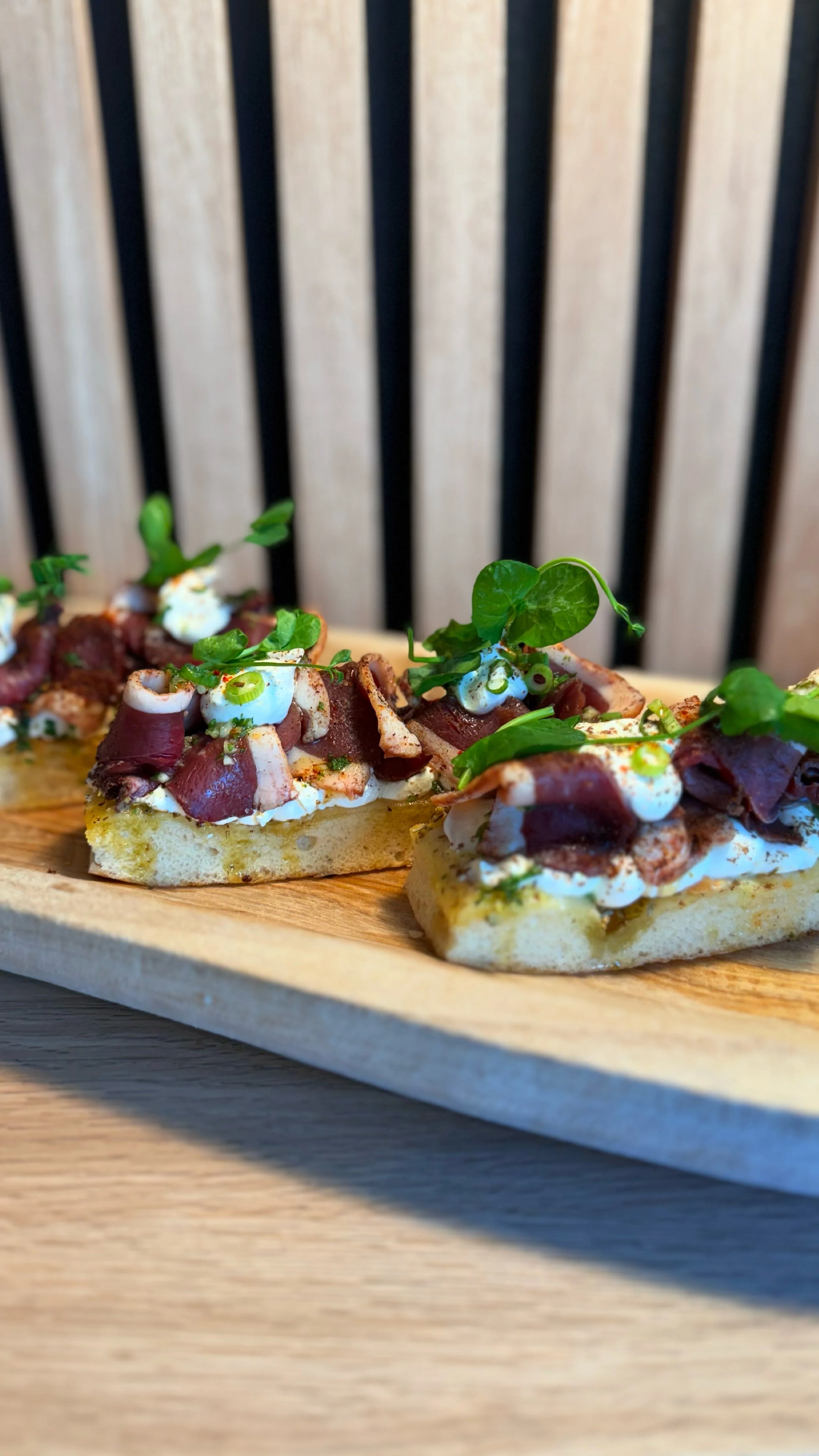 Focaccia garnie avec du jambon, de la crème, des herbes et des pousses.