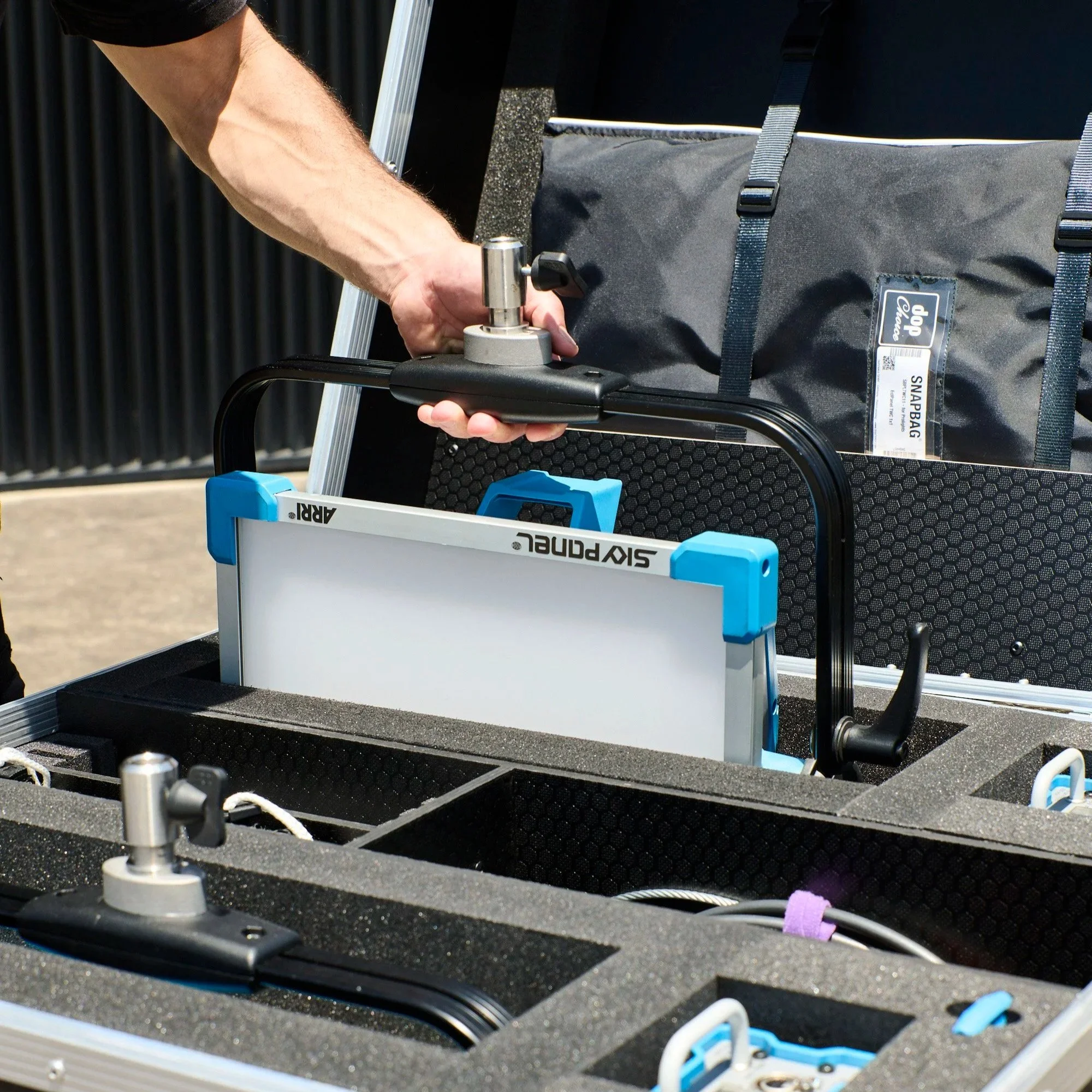 Close-up of a person's arm handling a Arri SkyPanel S30-C stored in a foam-lined custom road case.