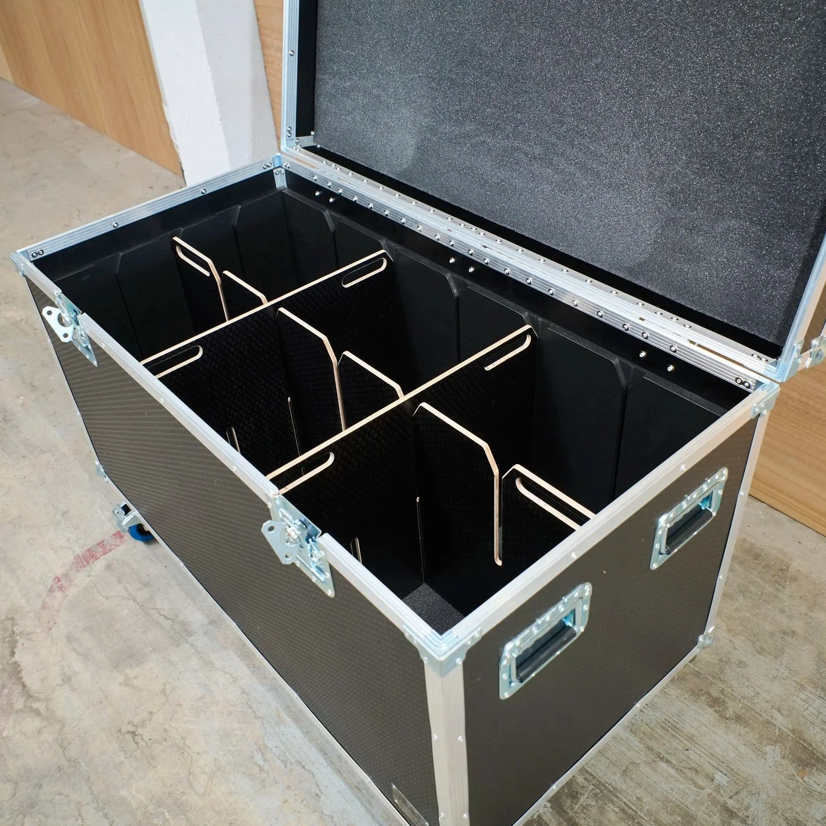 Open black road case with foam-lined interior and multiple dividers offering a number of compartments.