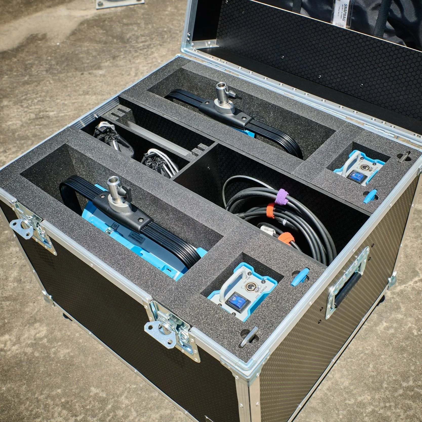 A metal case with foam compartments containing electronic equipment and cables, with some equipment installed and others stored inside.