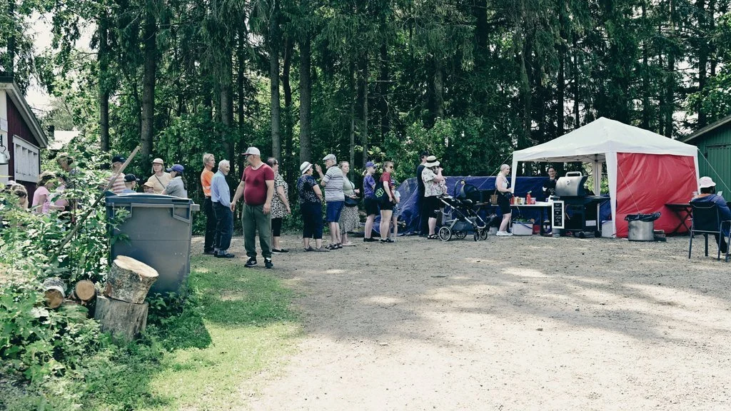 Ihmmiset jonottamassa telttakahvilaan kesäisellä pihalla