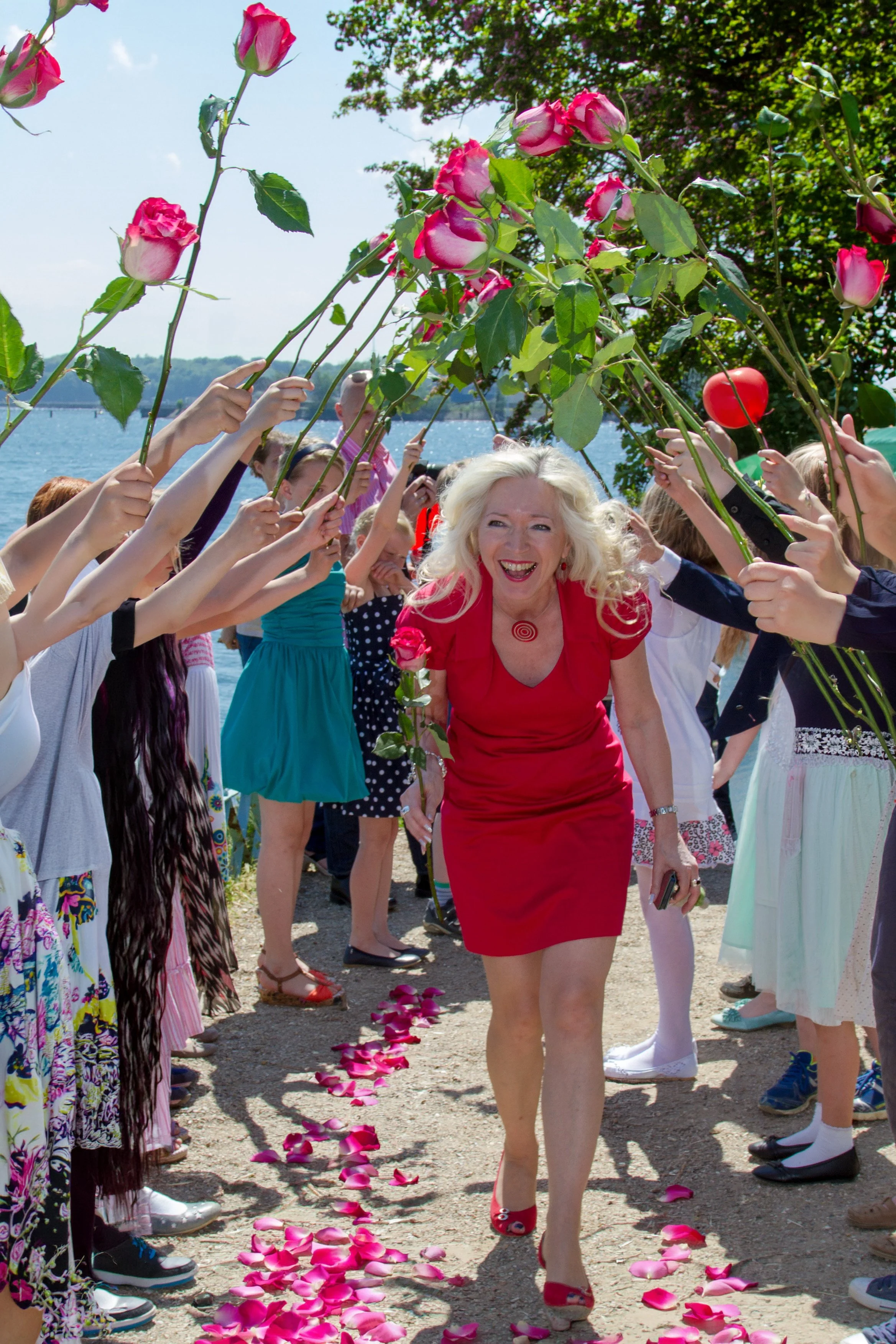 Freie Rednerin bei einer Trauung in Kiel geht lachend durch ein Rosenspalier.