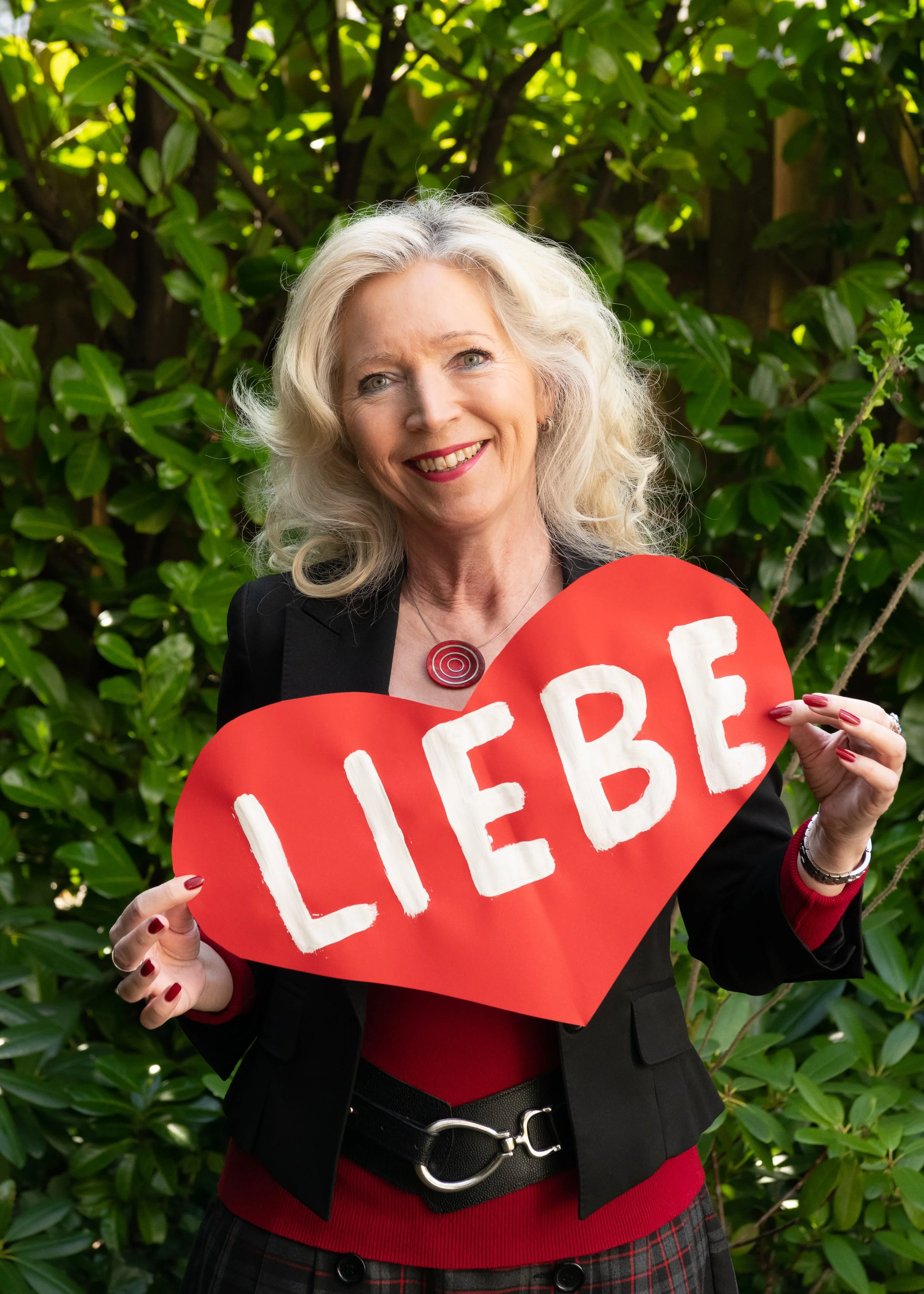 Freie Rednerin Angela Günther aus Kiel hält ein rotes Herz mit der Aufschrift Liebe und freut sich auf eine Trauung.
