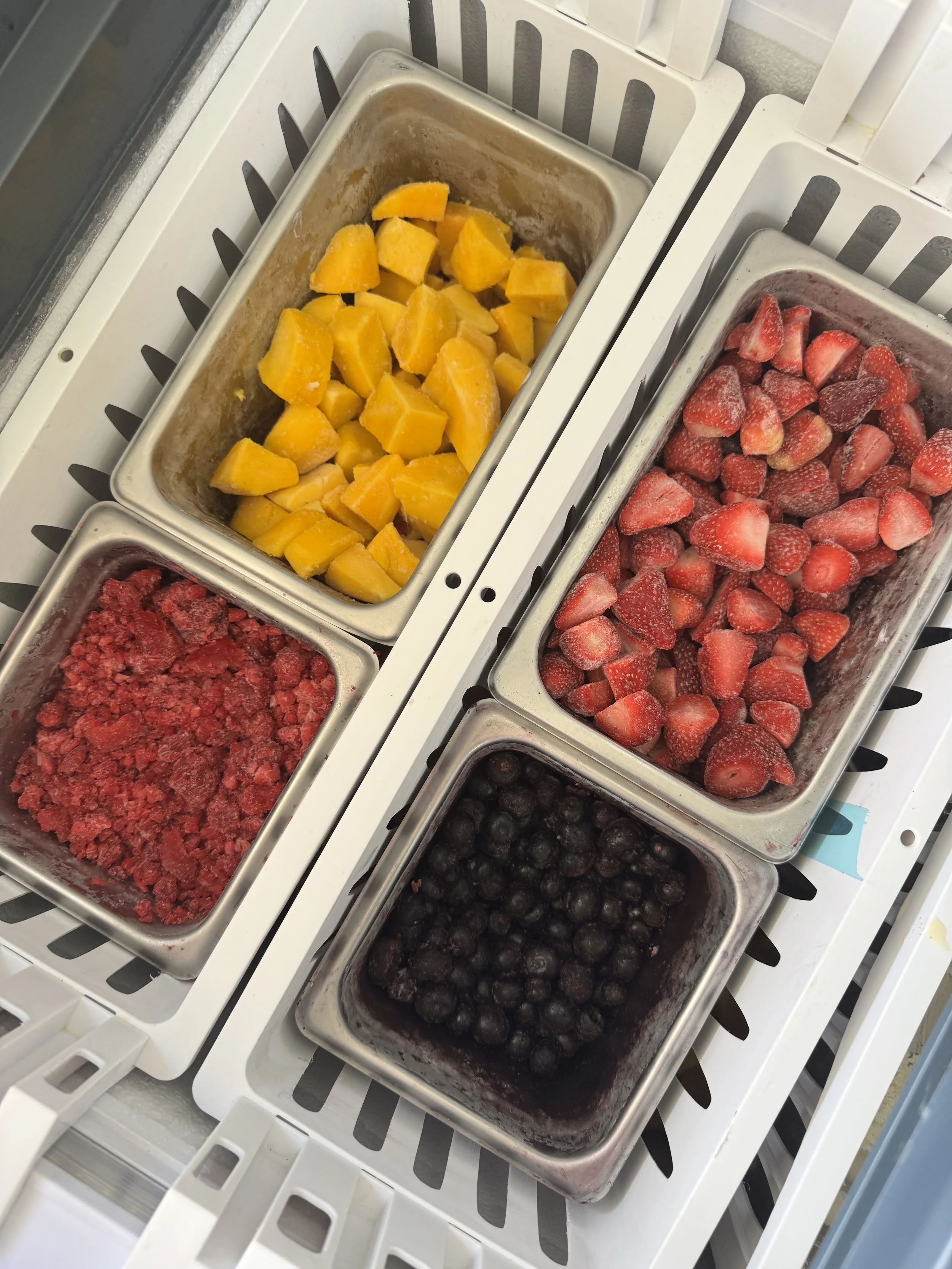 Frozen fruit selection including chunks of mango, strawberries, blueberries, and raspberries.