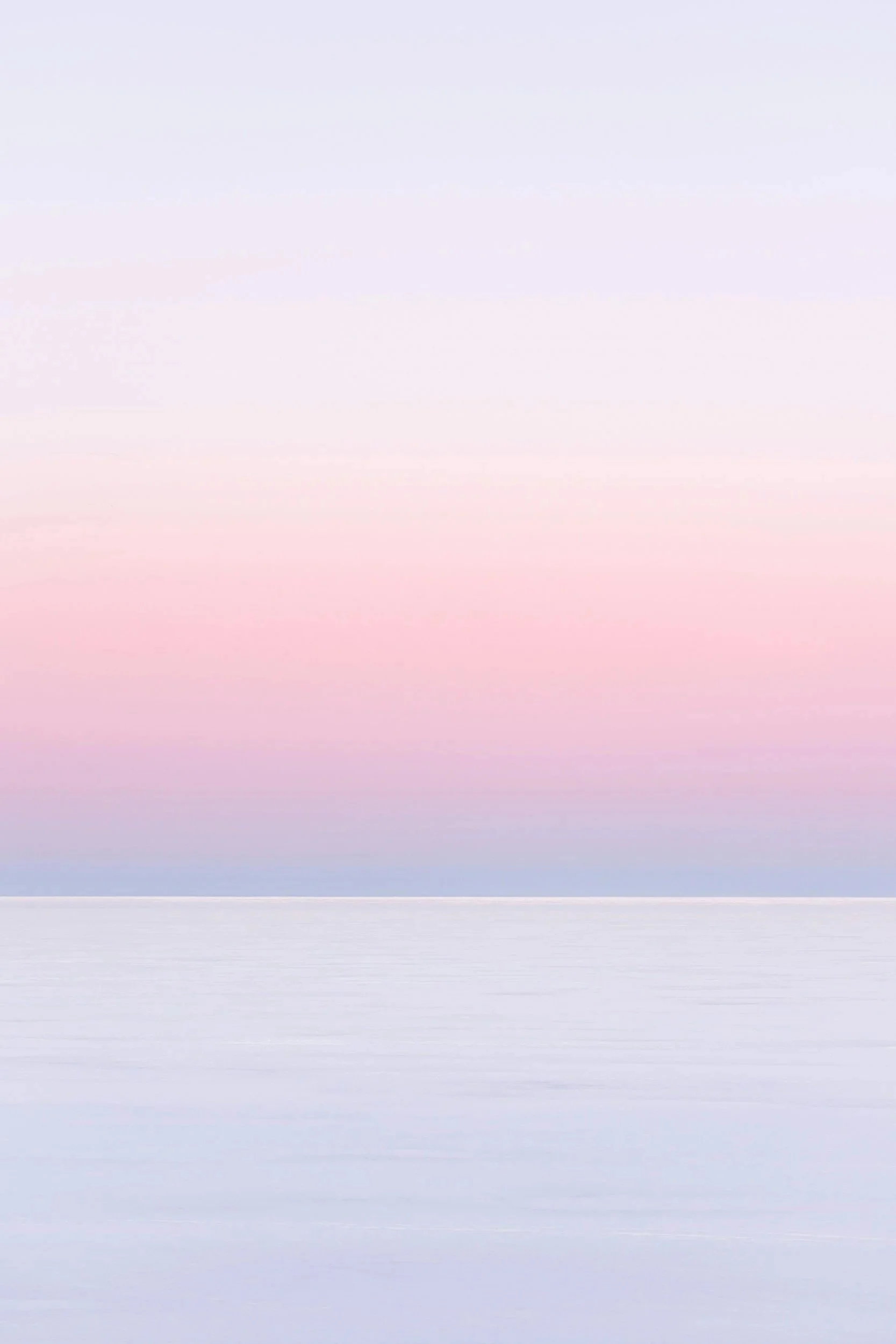 Nebeliger Himmel über einem ruhigen Wasser, Pastellfarben in Blau, Rosa und Lila.