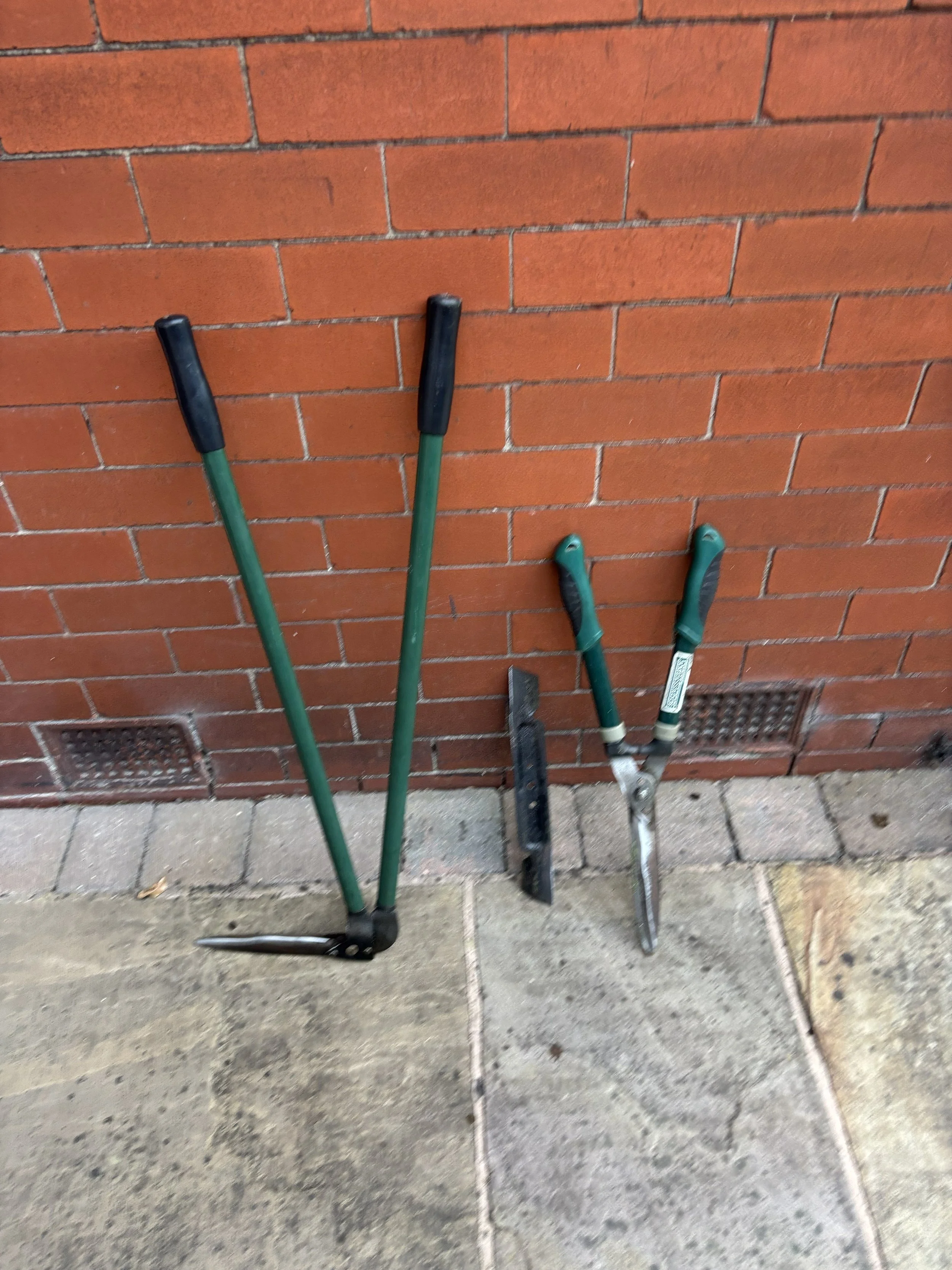 Professionally sharpened garden tools including lawn mower blade, grass edging shears, and hedge trimmers