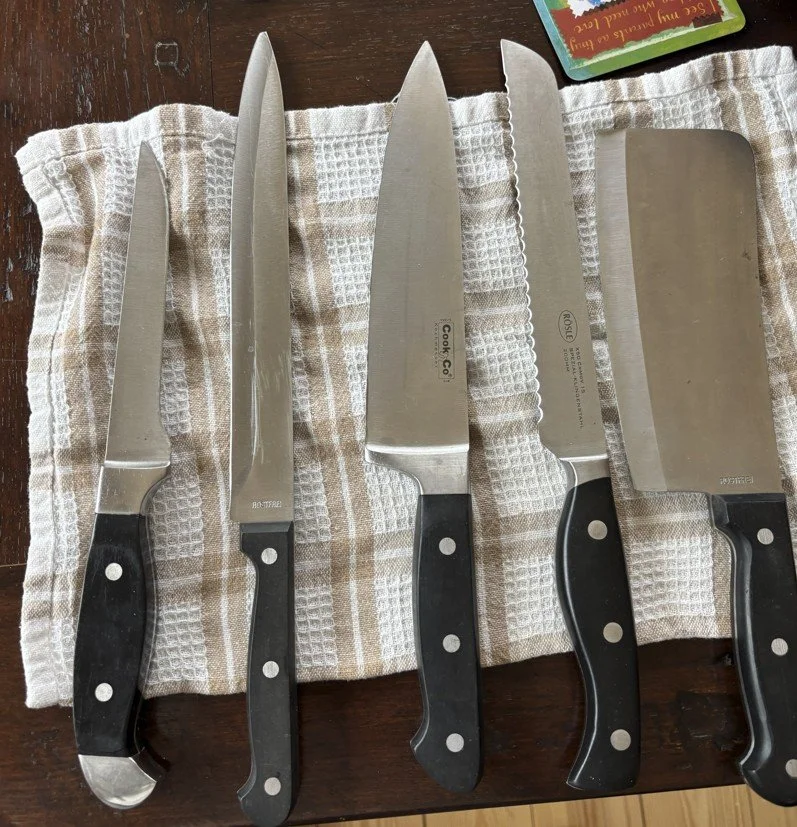 A set of kitchen knives including a serrated knife and cleaver