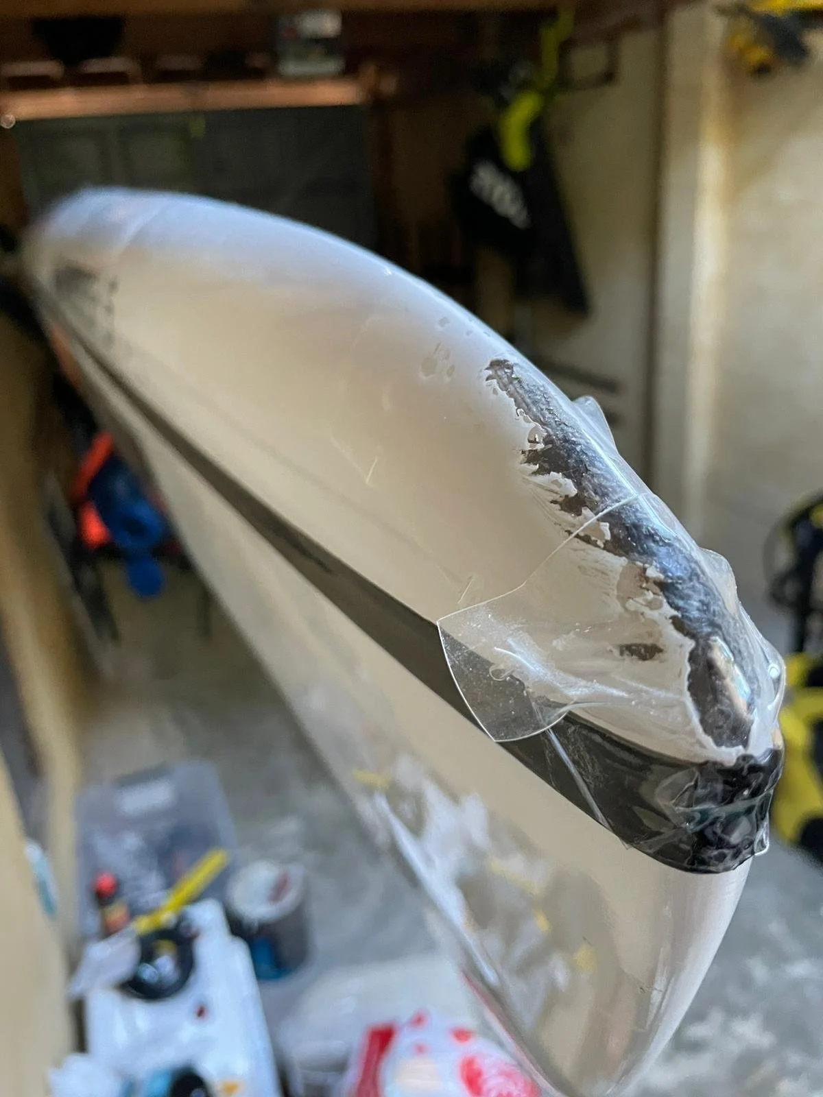 Close-up of a damaged clear plastic or acrylic surface, with scratches and torn edges.