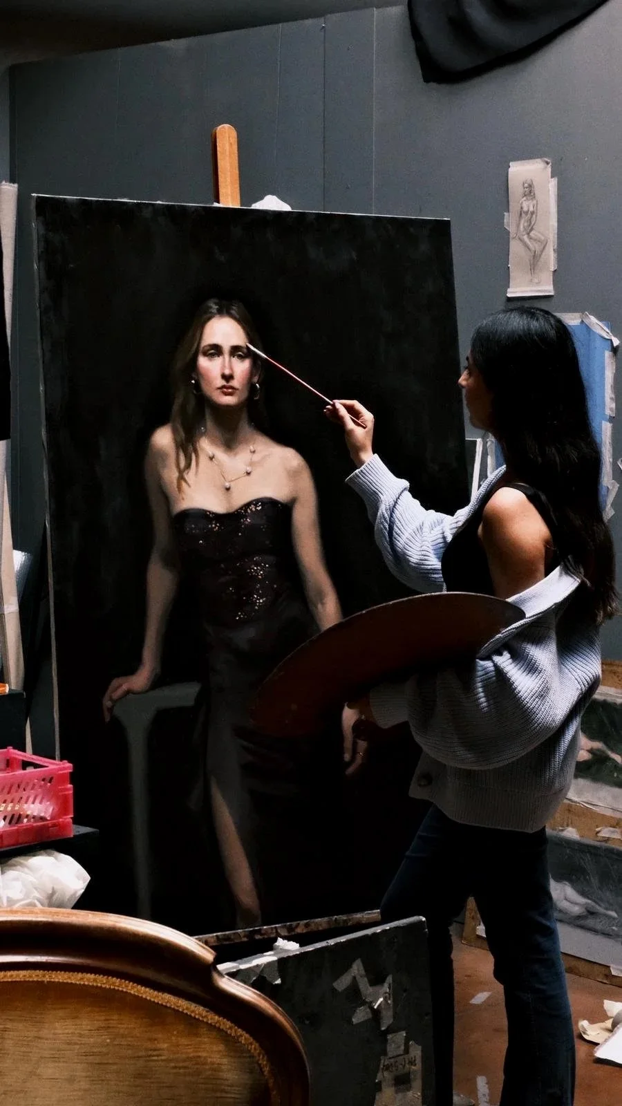 Una artista pintando un retrato realista de una mujer en un caballete en un estudio artístico.