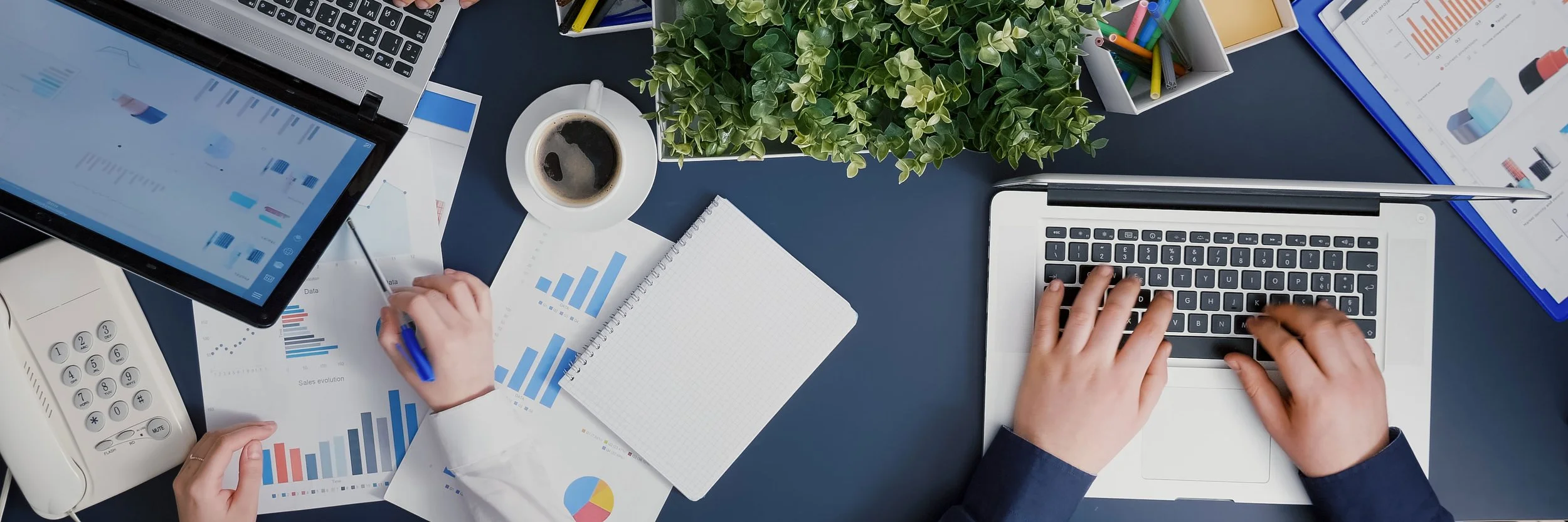 People work on their laptop while reviewing sales reports