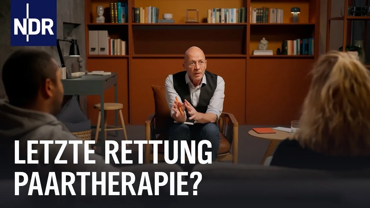 Thumbnail der NDR Serie "Die Paartherapie". Zu sehen ist der Paartherapeut Eric Hegmann in der Mitte. Links und Rechts sind die Hinterköpfe des Paares zu sehen.