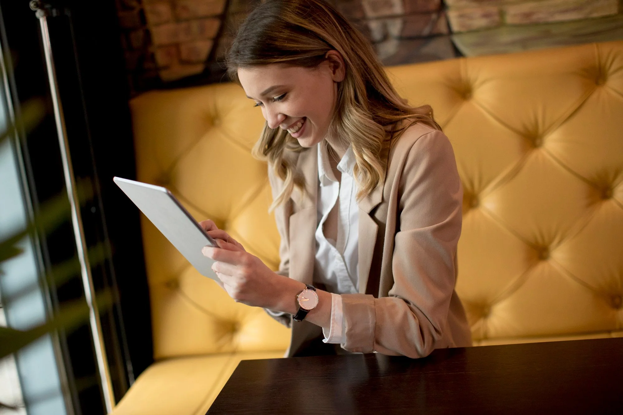 Duas pessoas de terno discutindo em uma reunião de trabalho, usando dispositivos eletrônicos, como tablet, smartphone e laptop, em um ambiente de escritório.