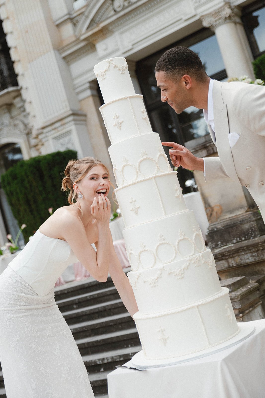 Bride and groom cutting a multi-tiered wedding cake outdoors. Documentary and loose editorial style wedding photography.