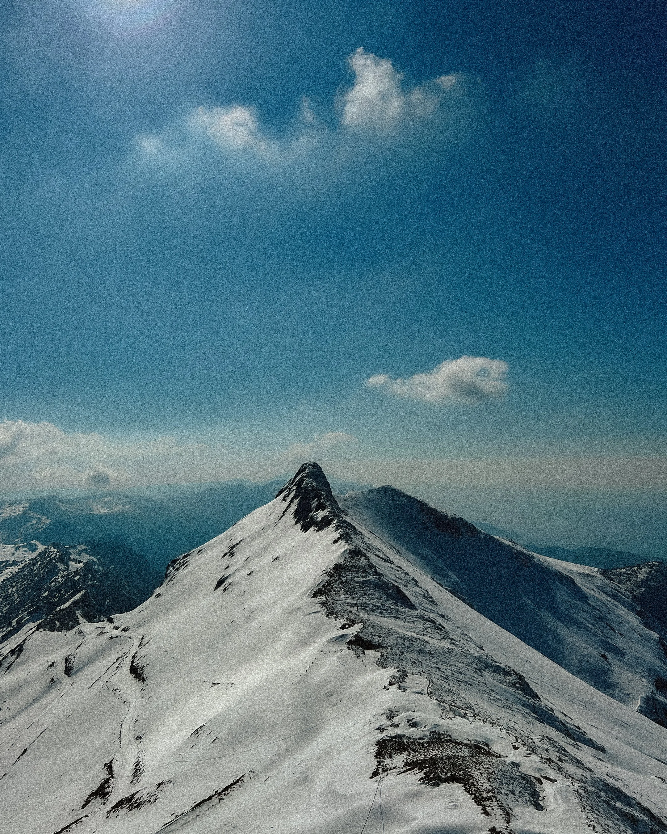 Snow-covered mountain peak under a blue sky with scattered clouds.