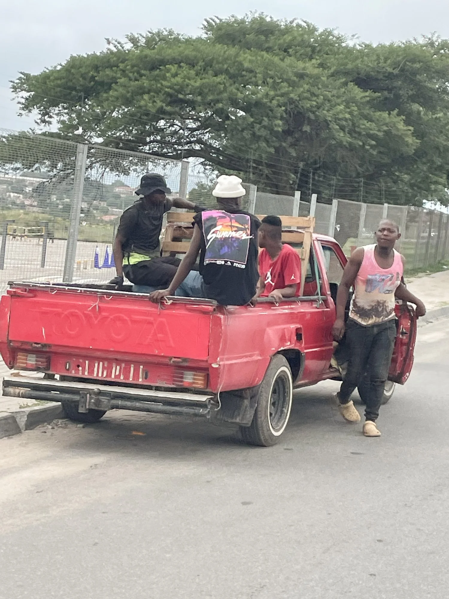 Mannen zitten achterin pick-up truck langs weg in Zuid-Afrika.