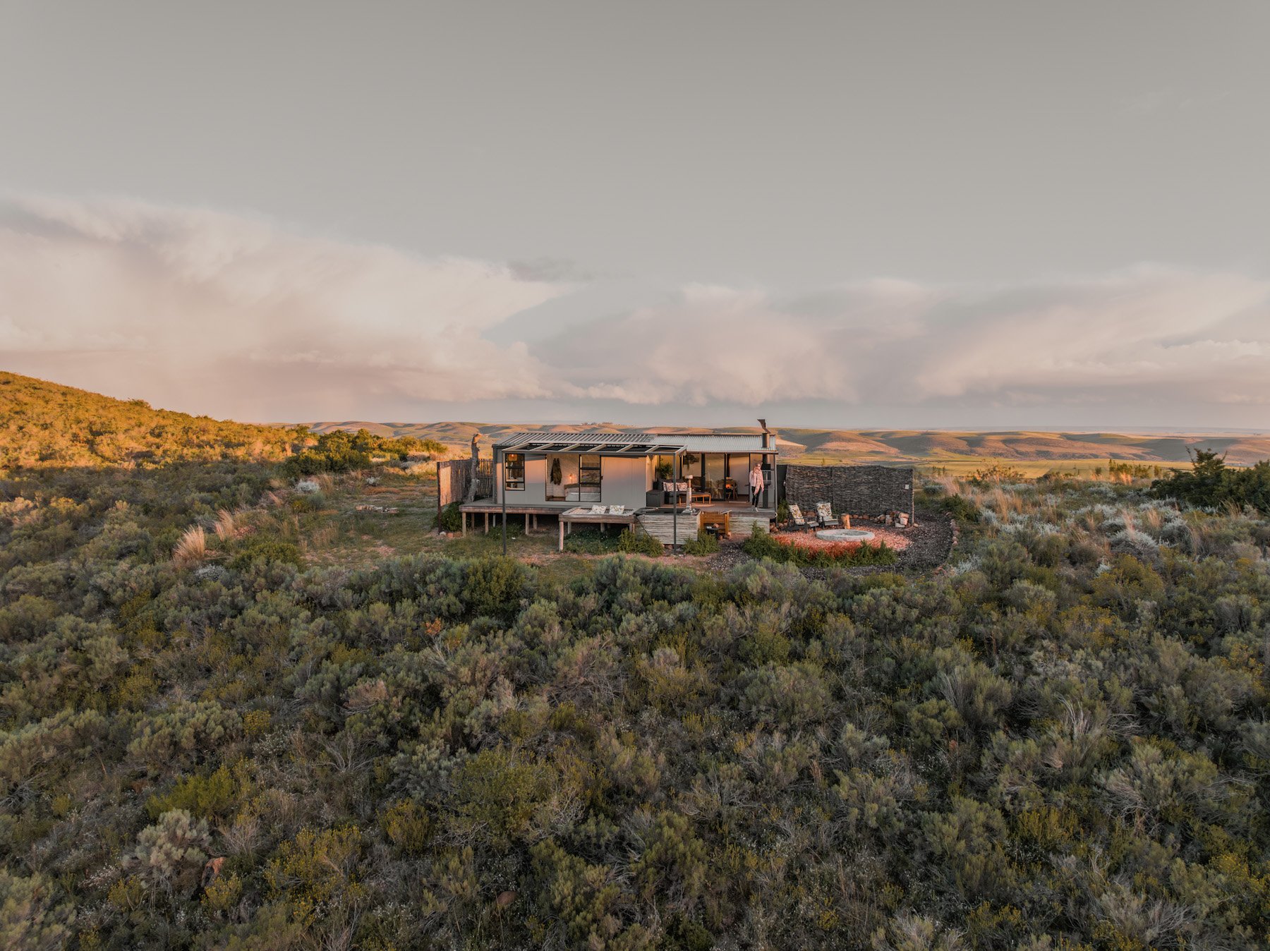 Eco cabin van Aviary Hills in ruig landschap tijdens gouden uur in Zuid-Afrika.