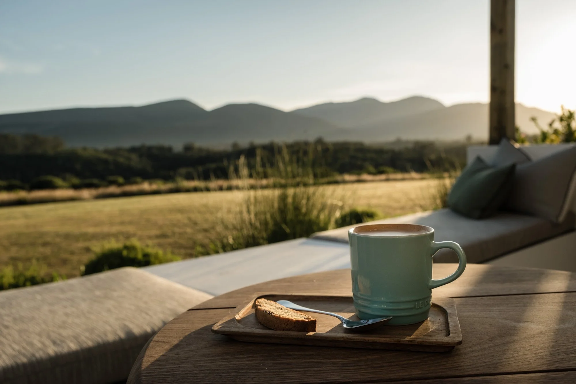 Kop koffie met koekje op houten tafel met uitzicht over vallei en bergen in The Crags.