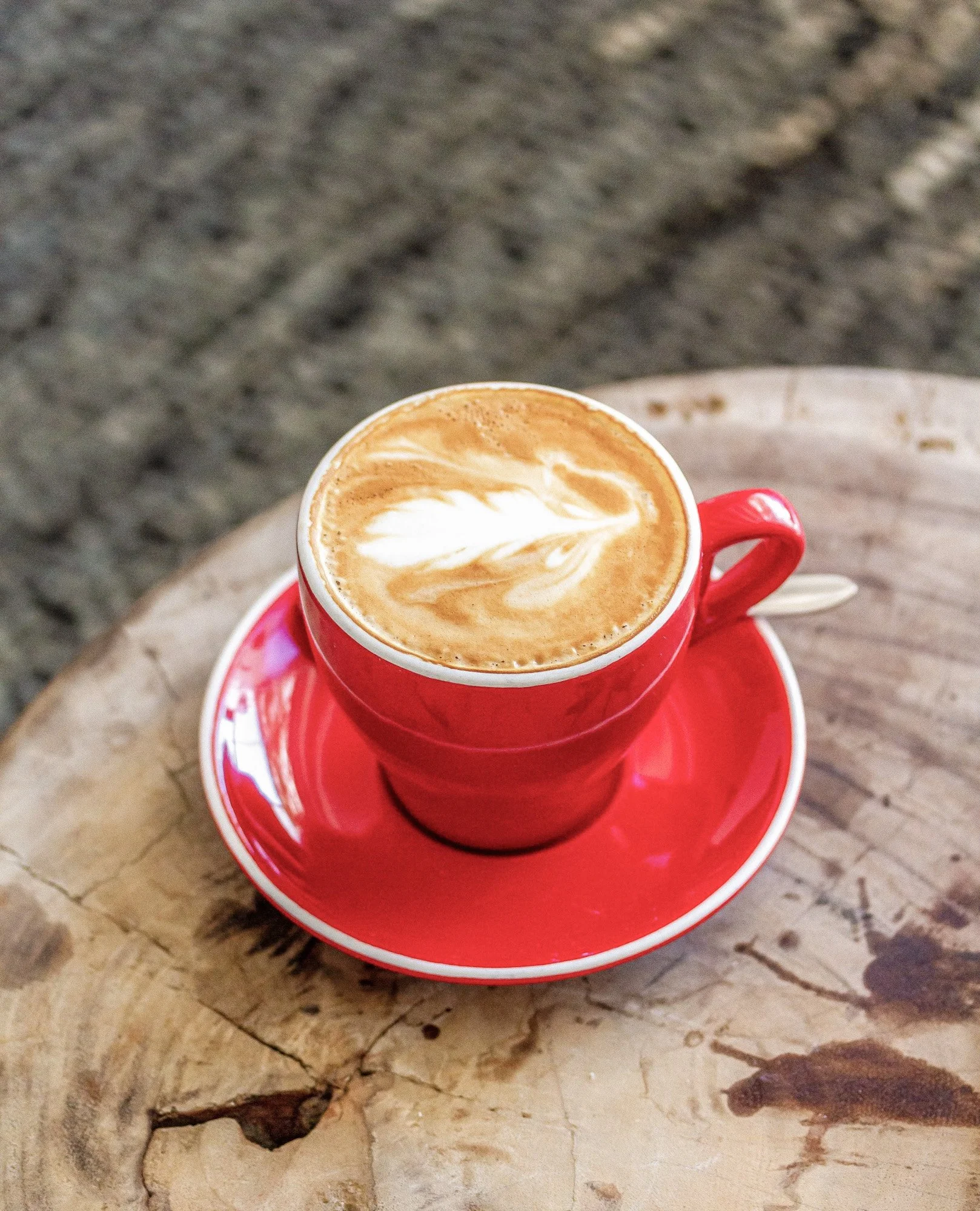 Kop koffie in rode mok op houten tafel van bovenaf gefotografeerd.